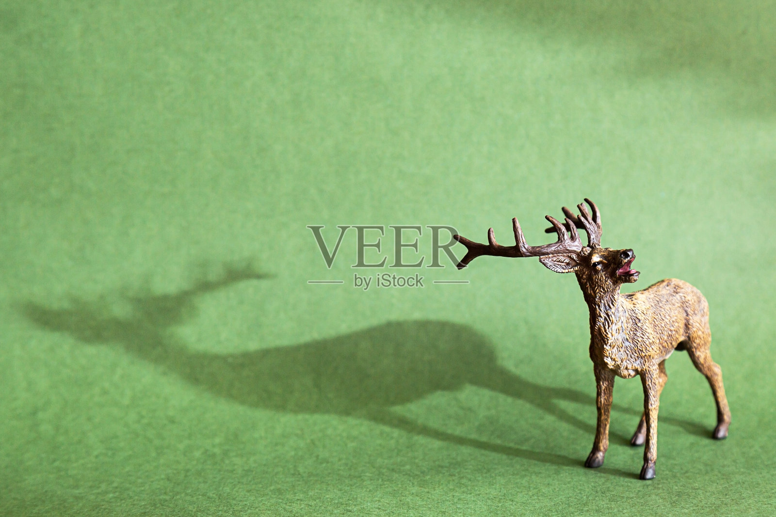 绿色背景上的鹿雕像。逼真的玩具，野生动物的复制品照片摄影图片