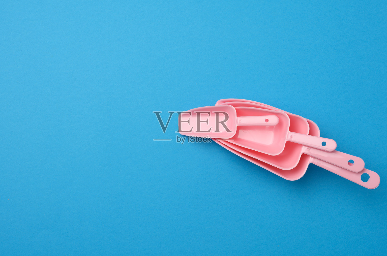 一套粉红色塑料厨房铲散装产品上的蓝色背景照片摄影图片