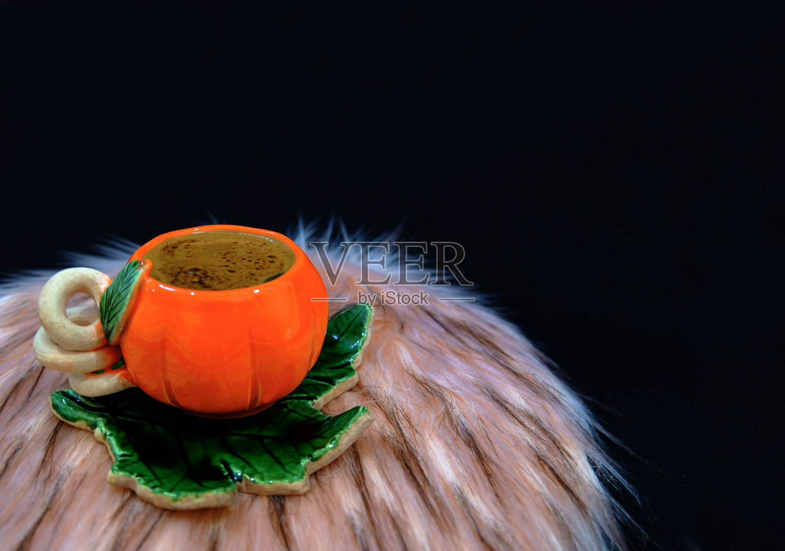 黑色背景毛茸茸的南瓜杯中闪闪发光的咖啡照片摄影图片