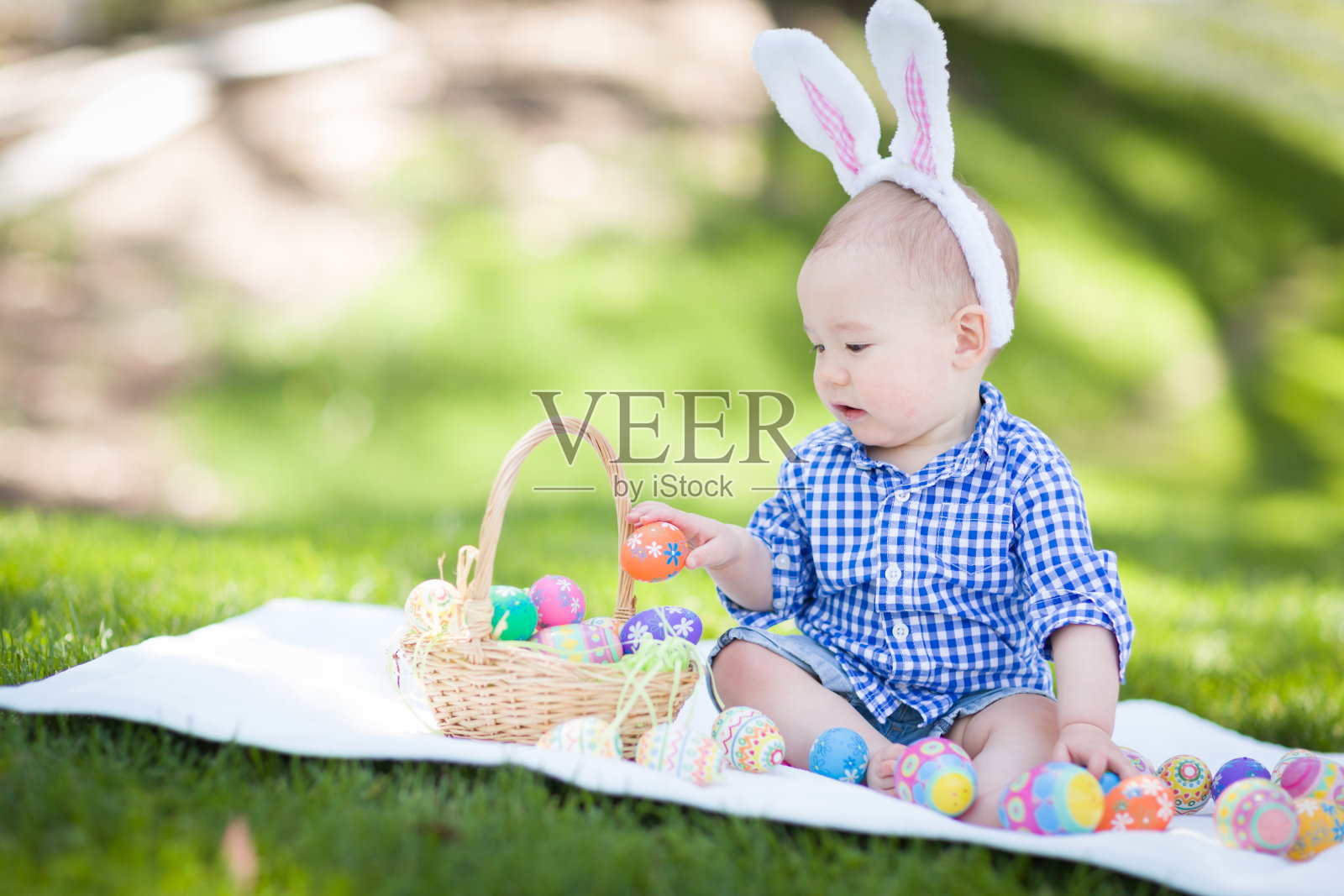 中国和高加索混血小男孩戴着兔子耳朵在外面玩复活节彩蛋照片摄影图片