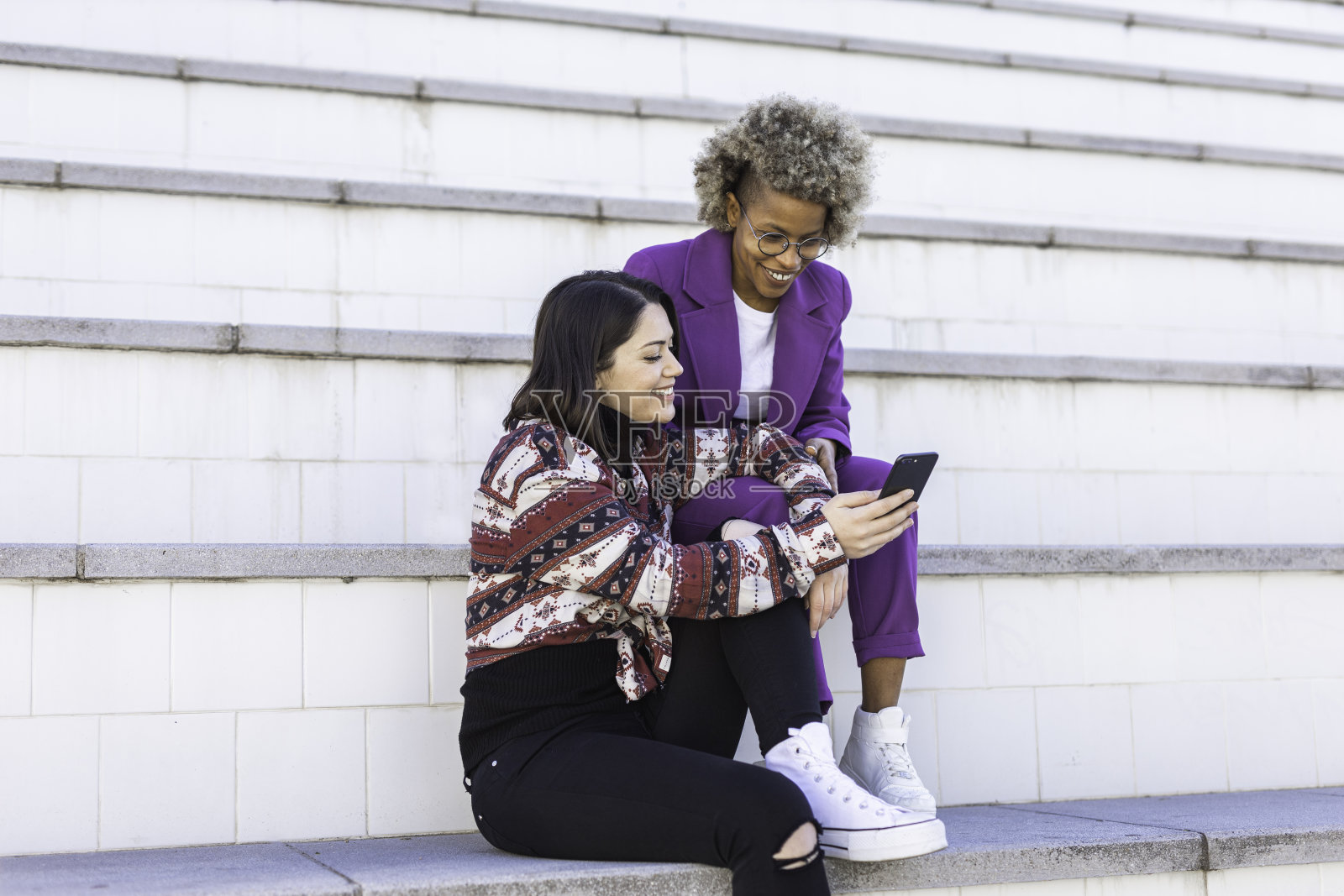 两个年轻迷人的多种族朋友与手机。照片摄影图片