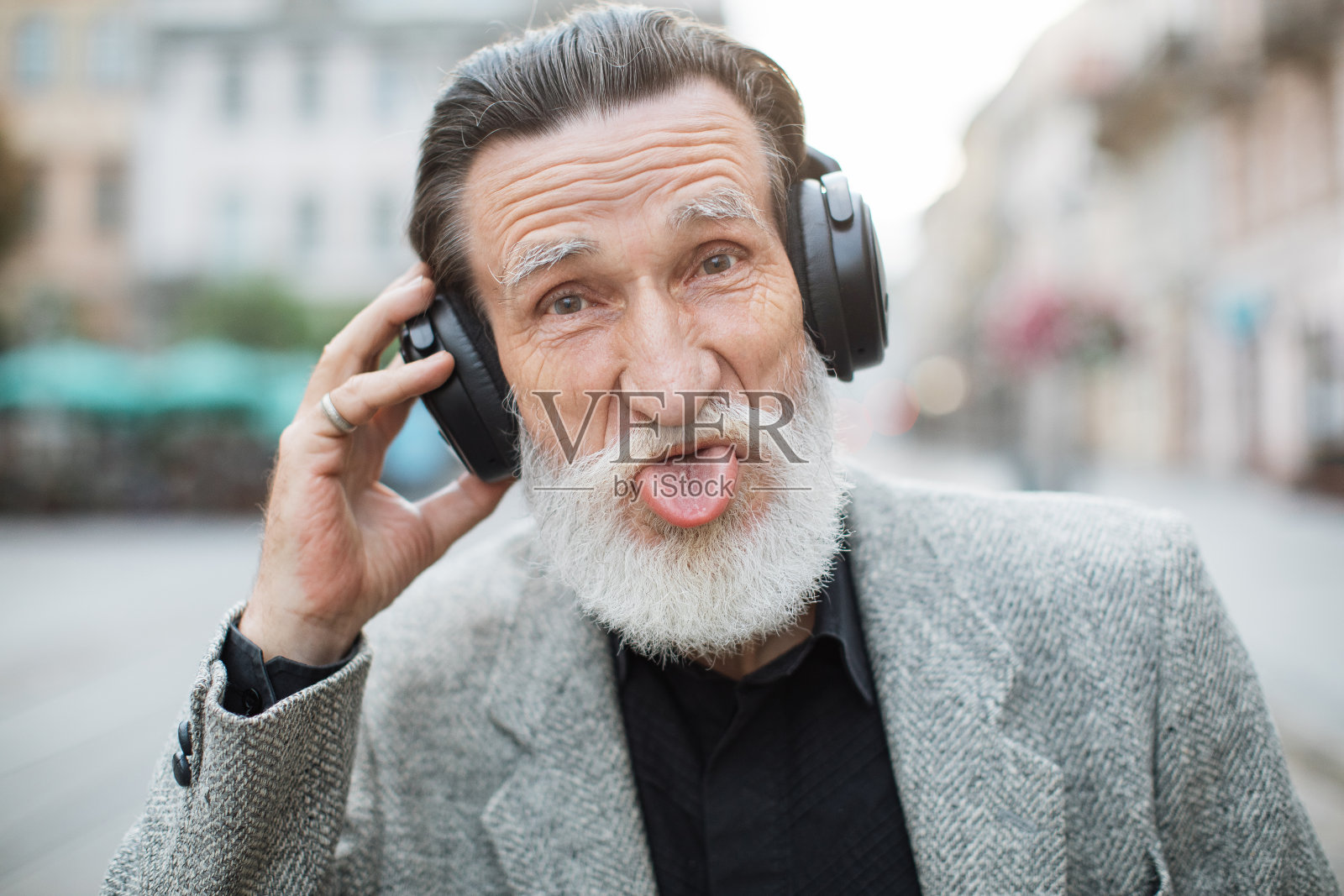 戴着耳机露出舌头的滑稽老人照片摄影图片