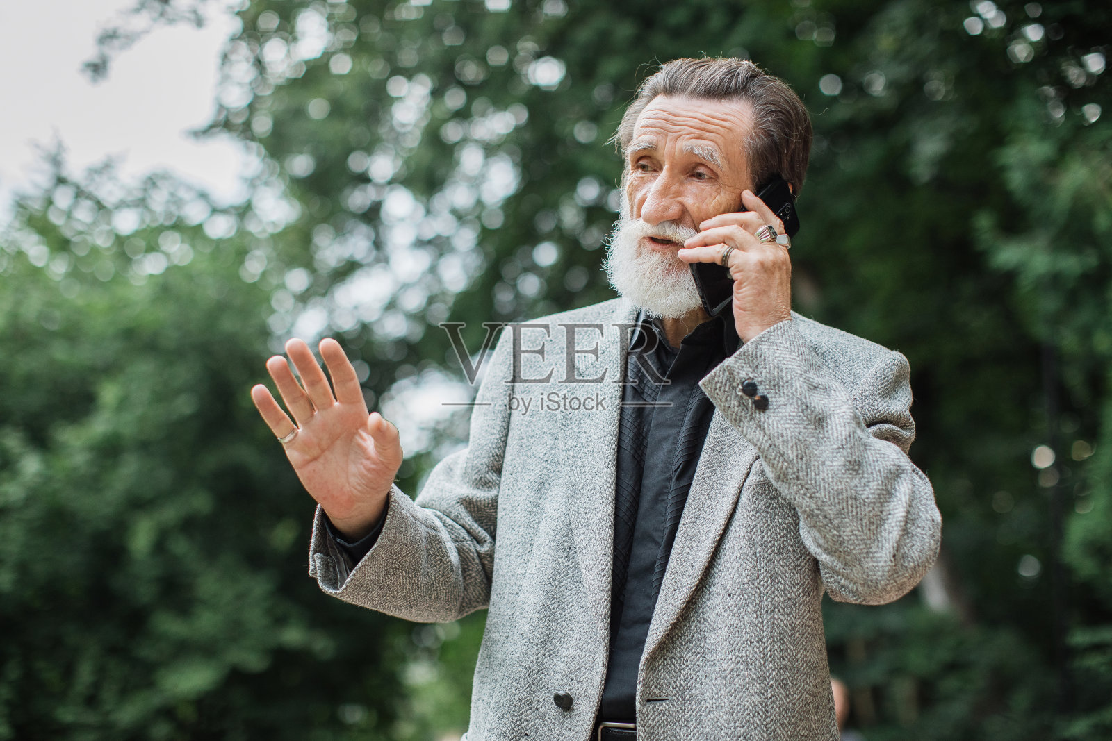 成熟的男人站在公园里打手机照片摄影图片