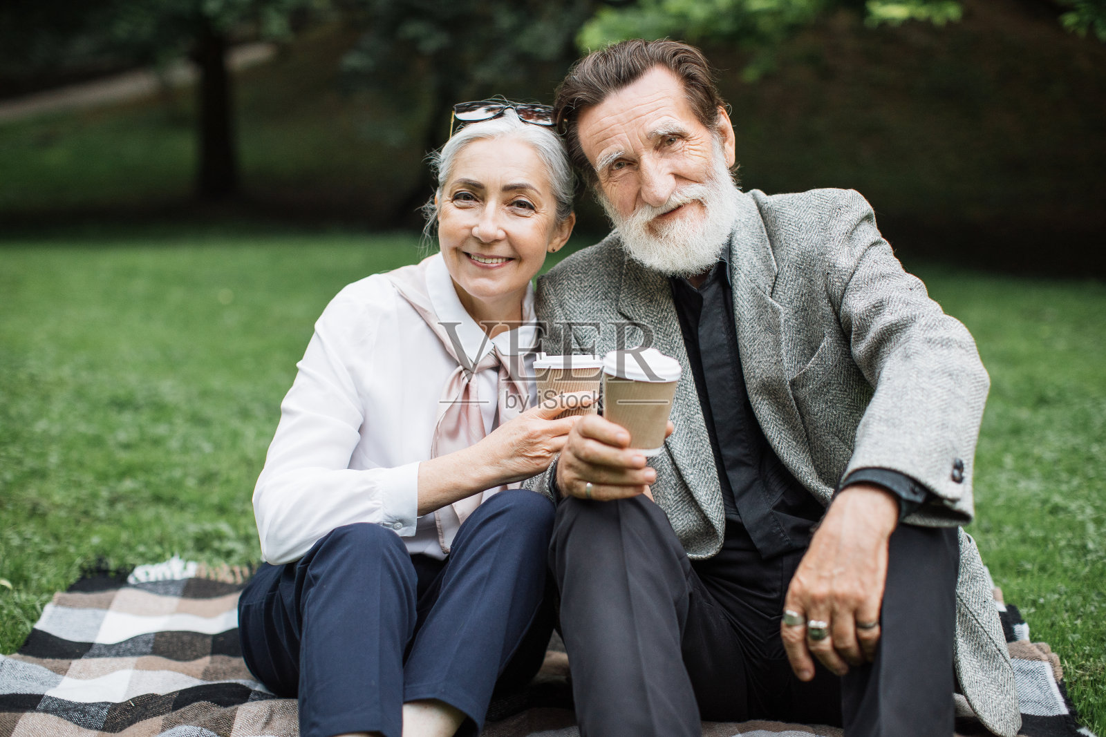 老夫妇坐在毯子上，喝着咖啡照片摄影图片