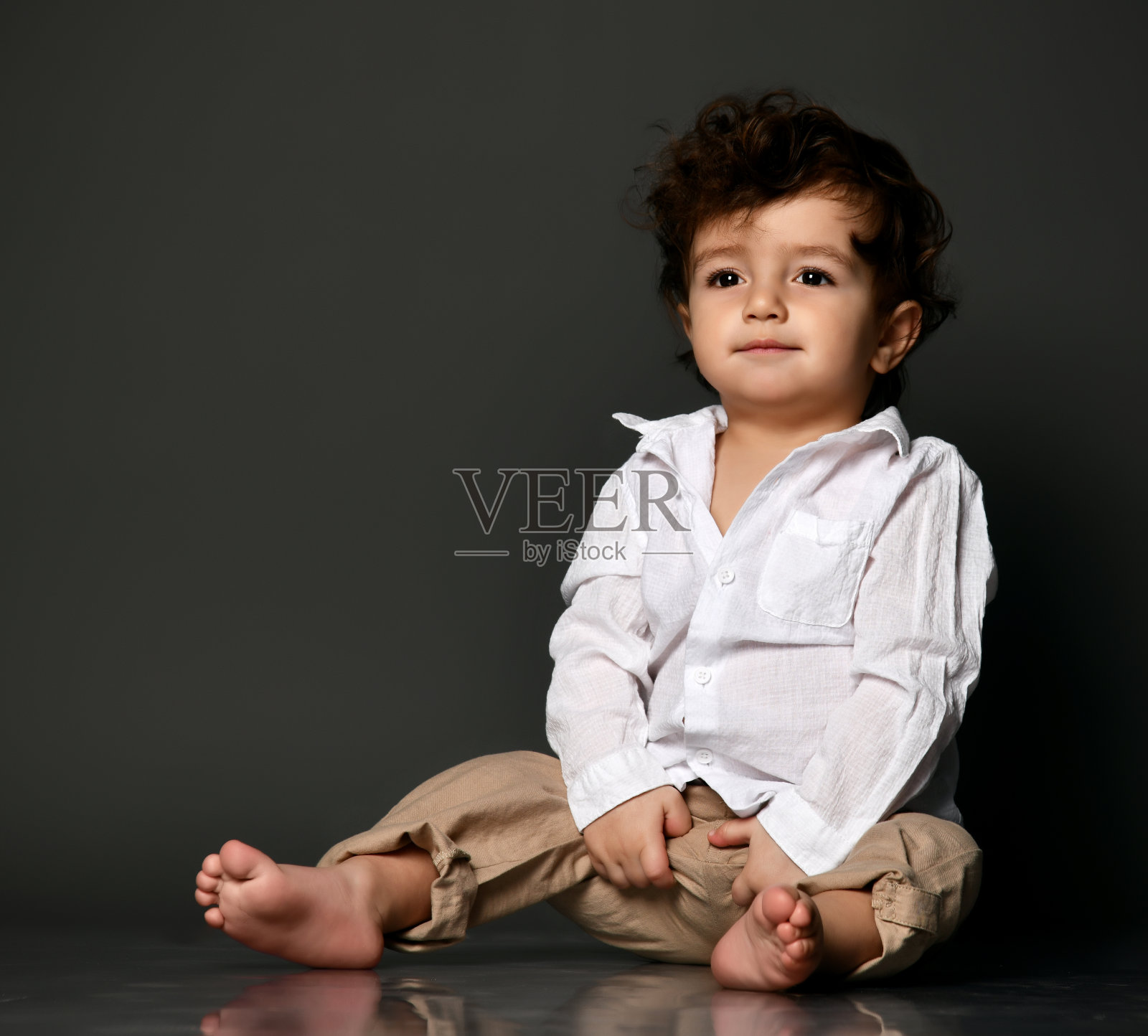 严肃时尚的婴儿坐在地板上看相机拍摄的人像照片摄影图片