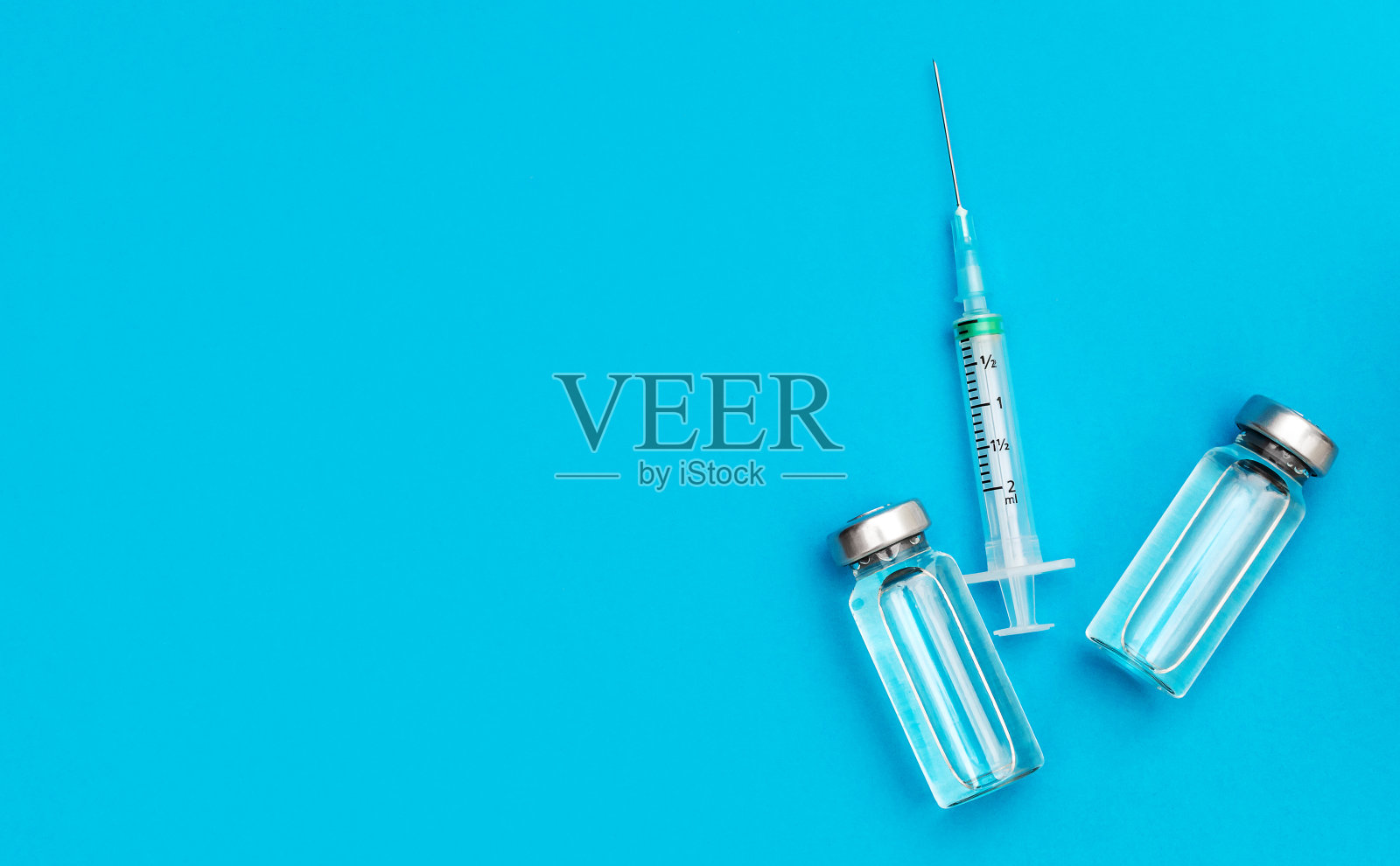 两个疫苗瓶和蓝色背景的注射器。COVID-19接种疫苗。前视图。空间的文本。照片摄影图片