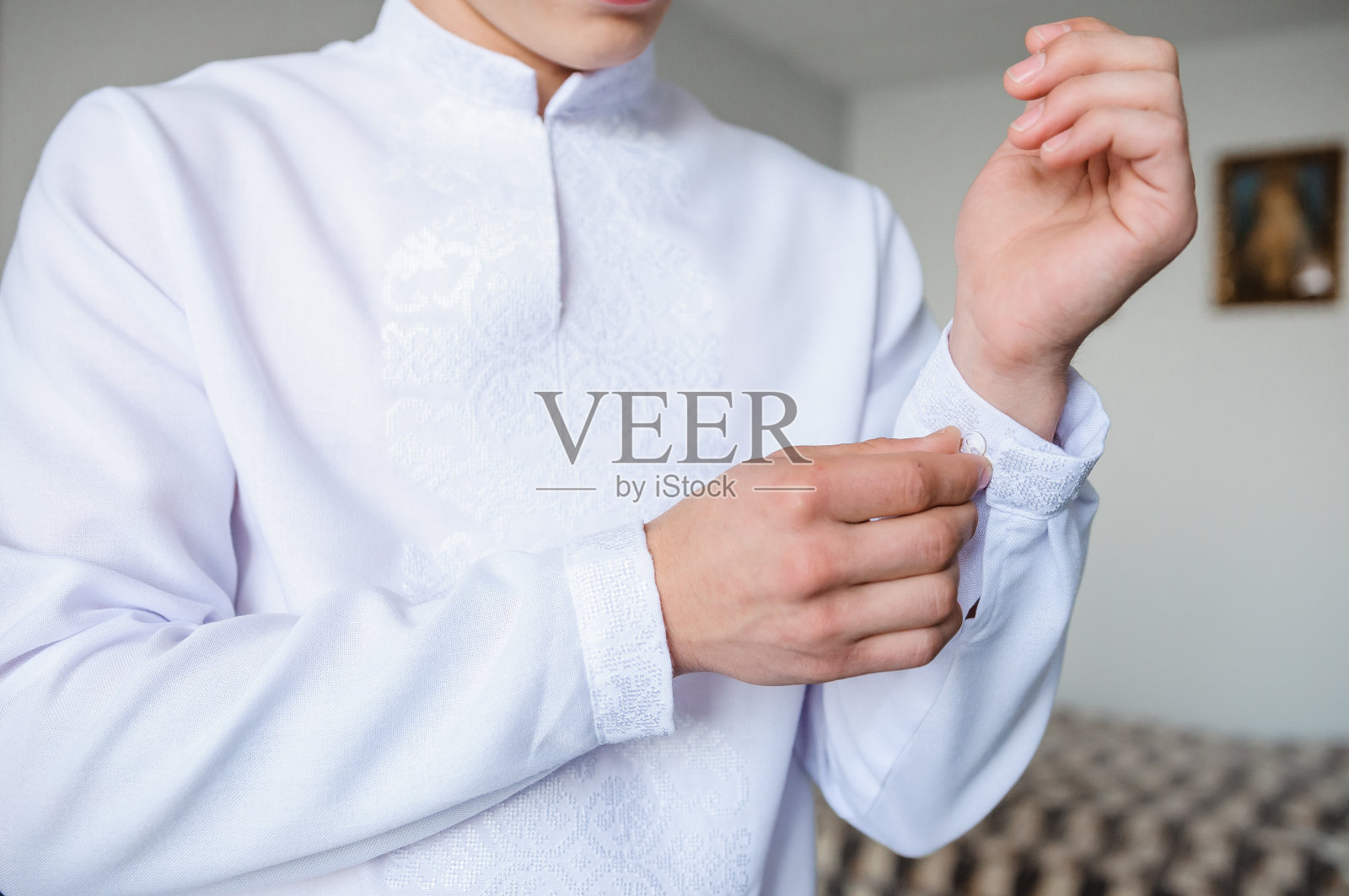 那人把袖扣扣在衬衫袖子上。新郎在他的衬衫袖子上扣上一颗纽扣照片摄影图片