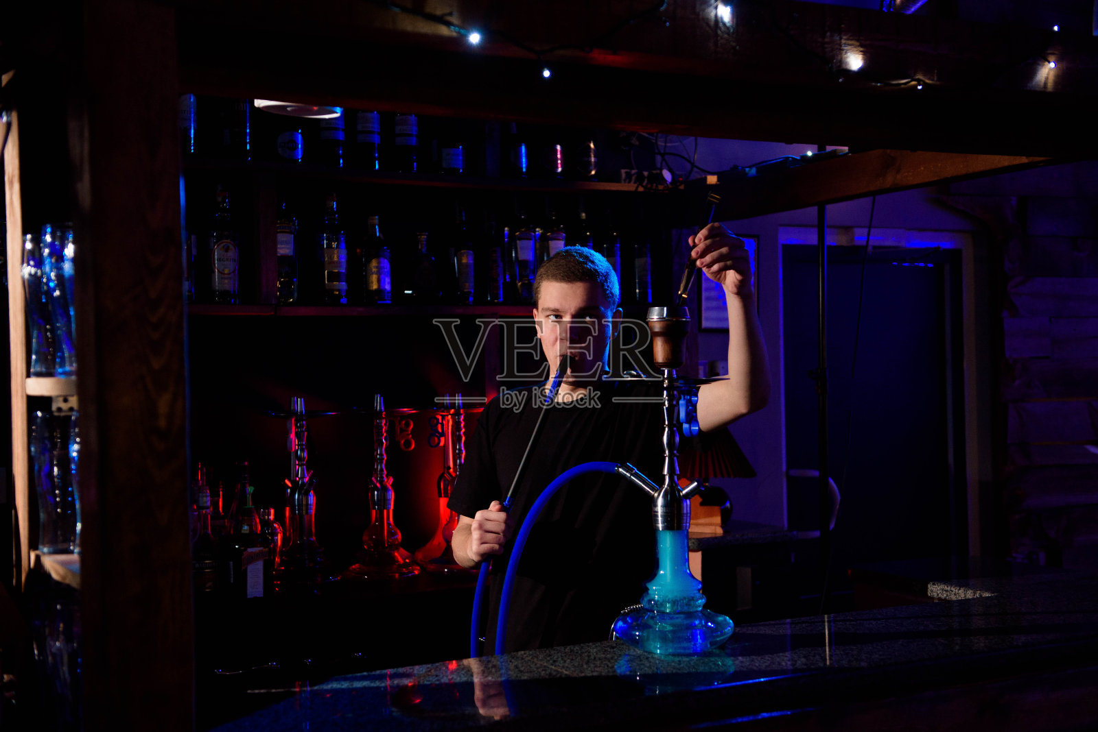 男子抽传统的水烟管，在水烟咖啡馆吐出烟雾。照片摄影图片