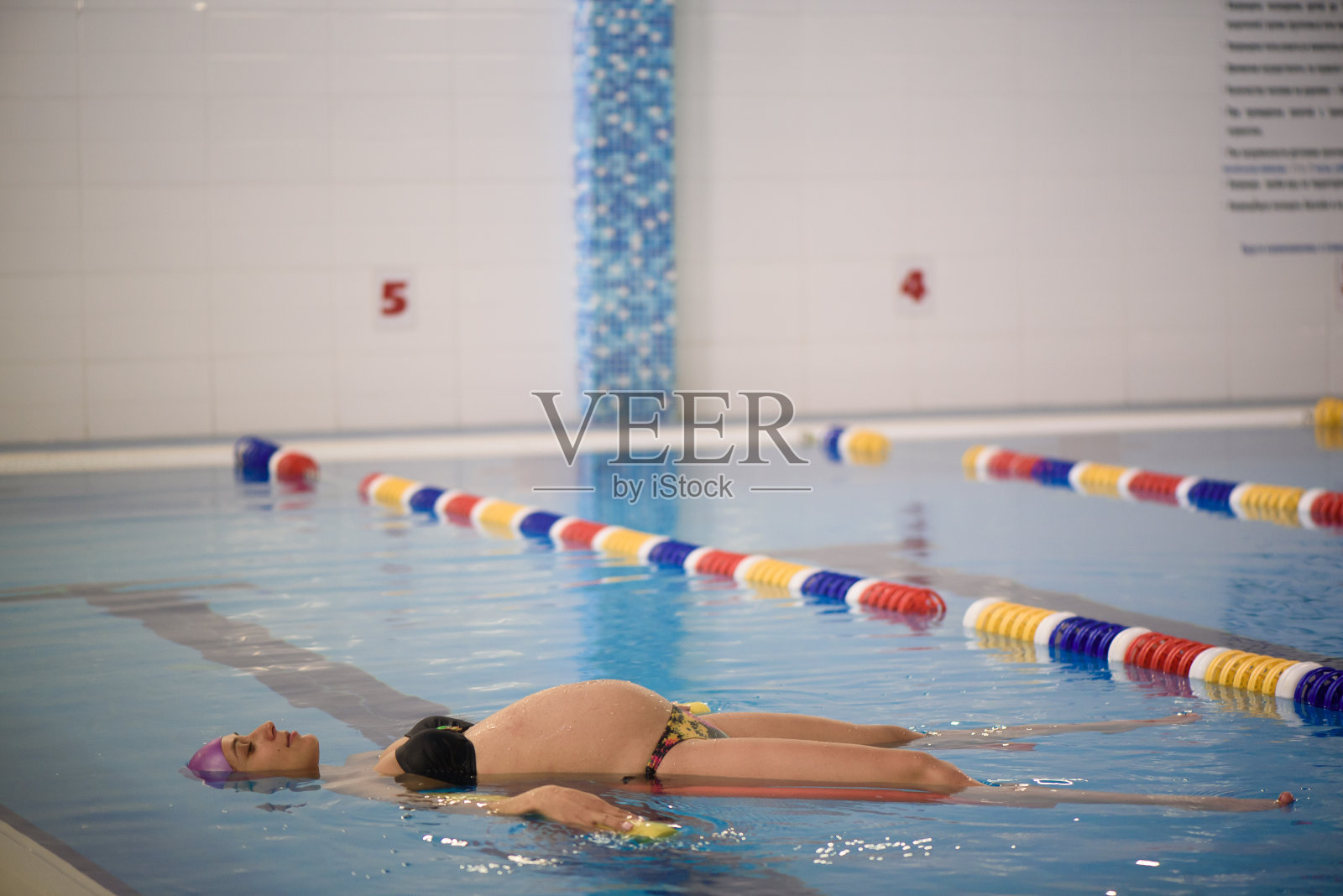 水中瑜伽，一名孕妇在泳池边做瑜伽练习照片摄影图片