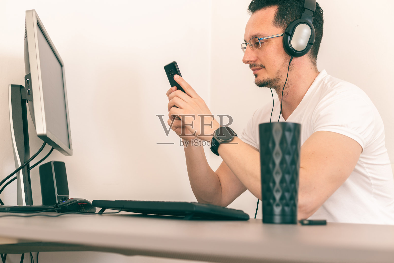 年轻的商人在他的家庭办公室里戴着耳机照片摄影图片