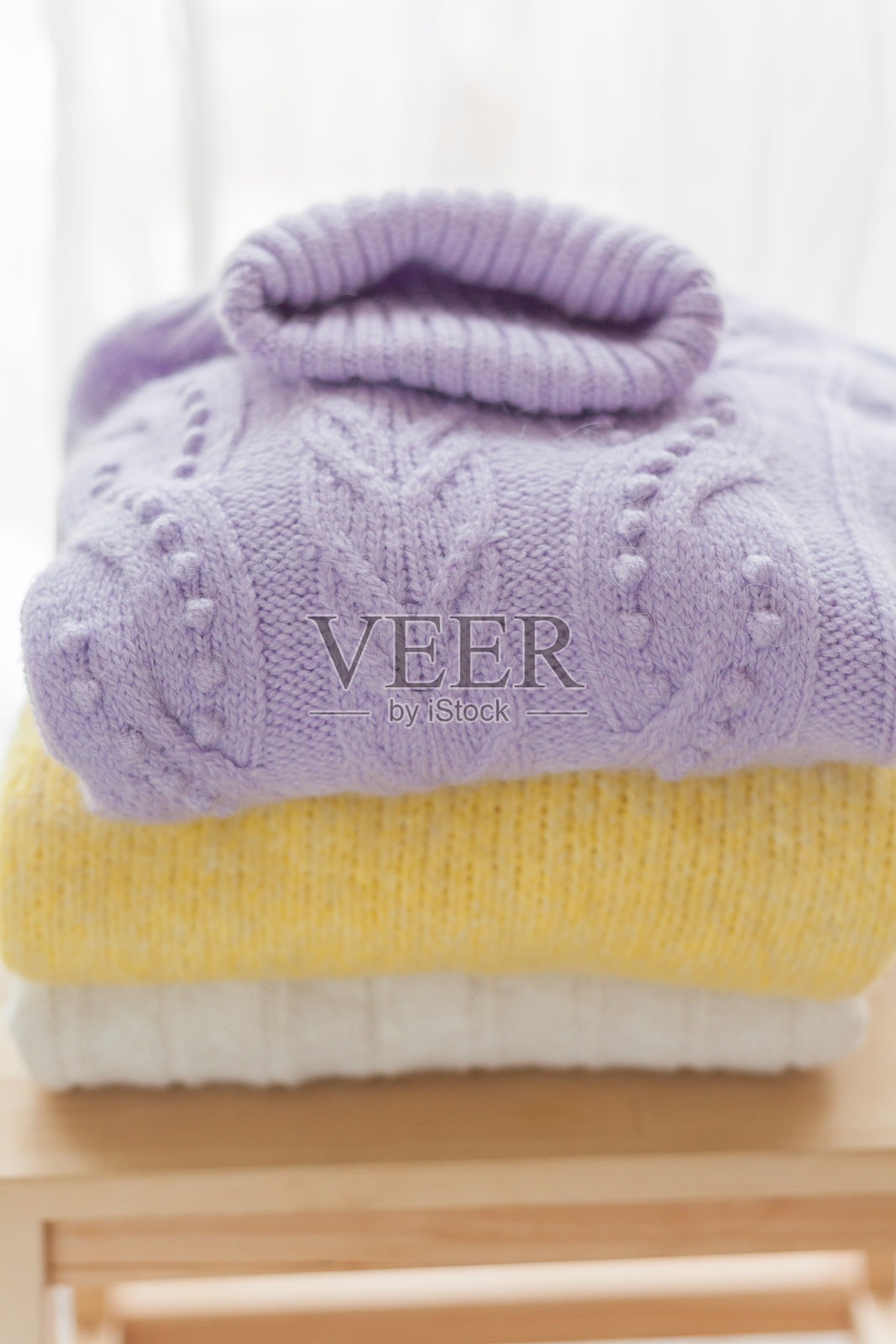 木椅上的一堆春装。黄色,紫色的颜色。舒适。照片摄影图片