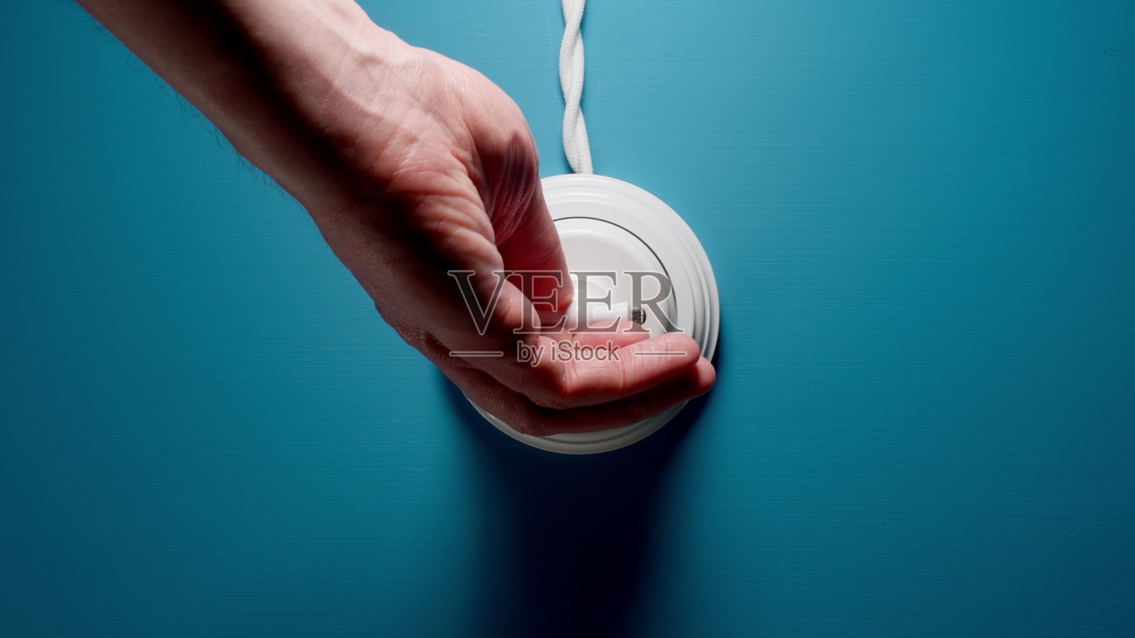 在蓝色墙壁上的一个拨动开关上的男性手开关照片摄影图片