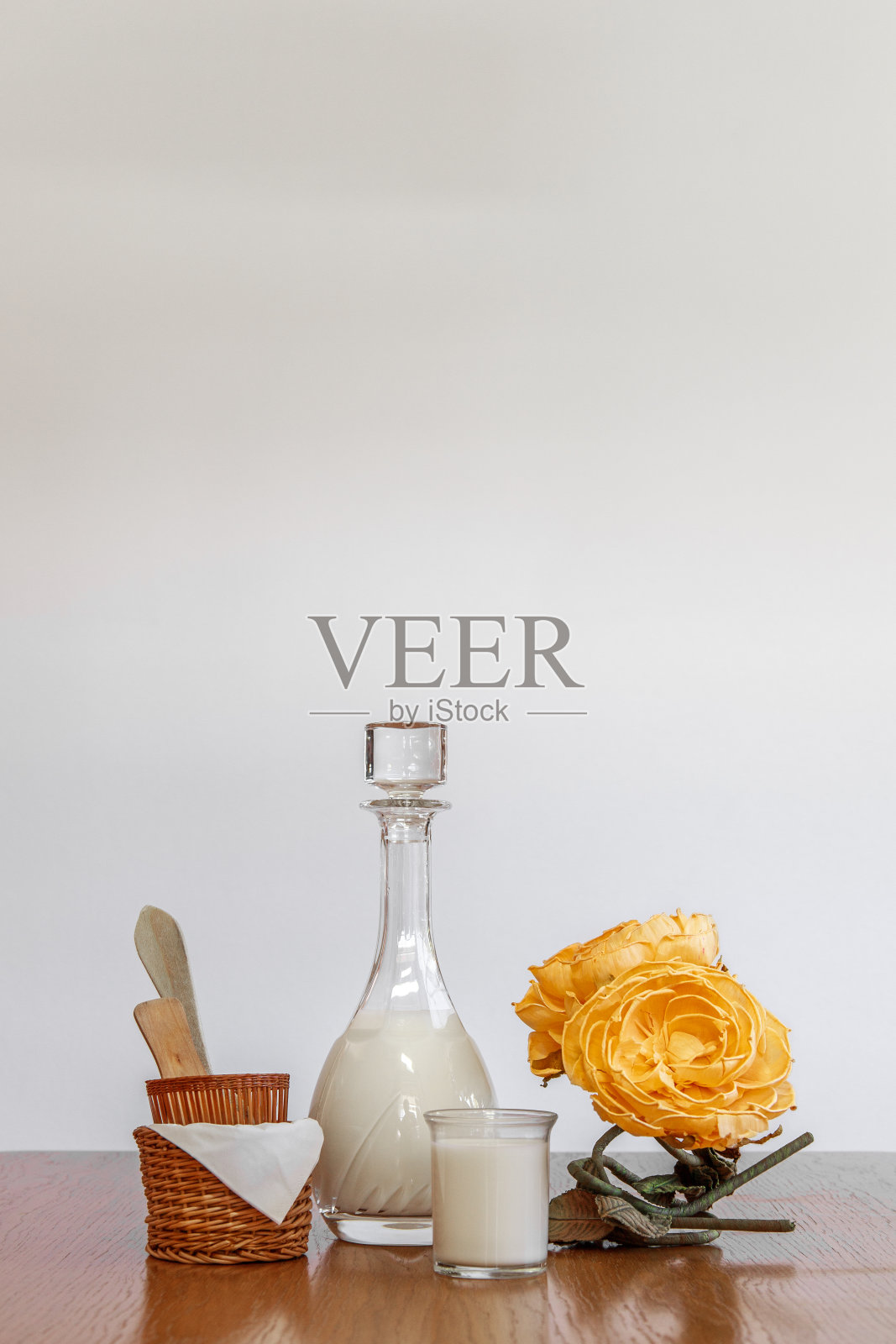 垂直的白色copyspace牛奶瓶和玻璃杯，黄色的花和篮子照片摄影图片