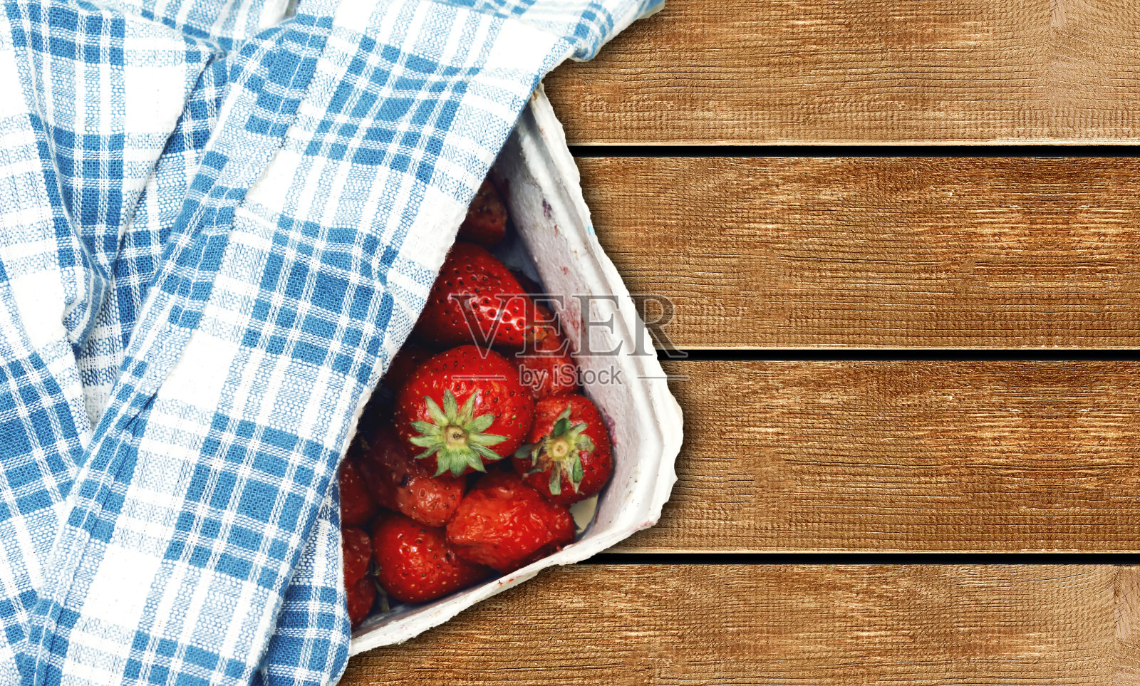 木桌上放着一盒新鲜采摘的草莓照片摄影图片