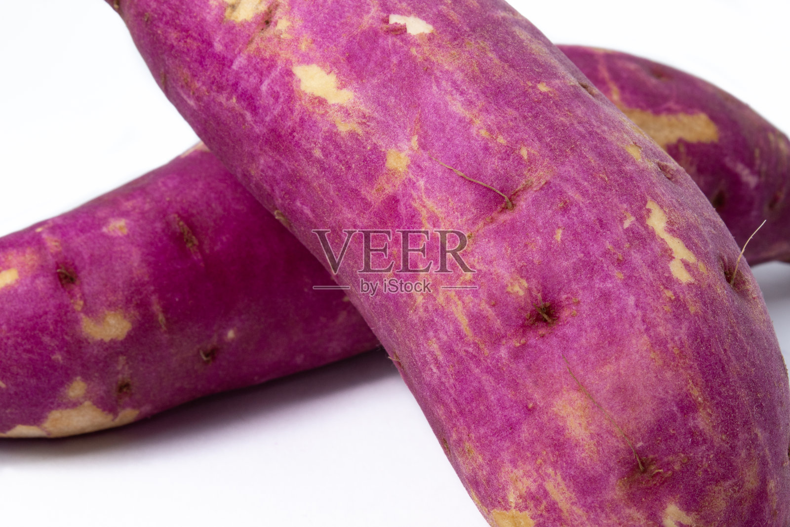 靠近堆叠和生的日本紫甘薯根，在白色的背景照片摄影图片