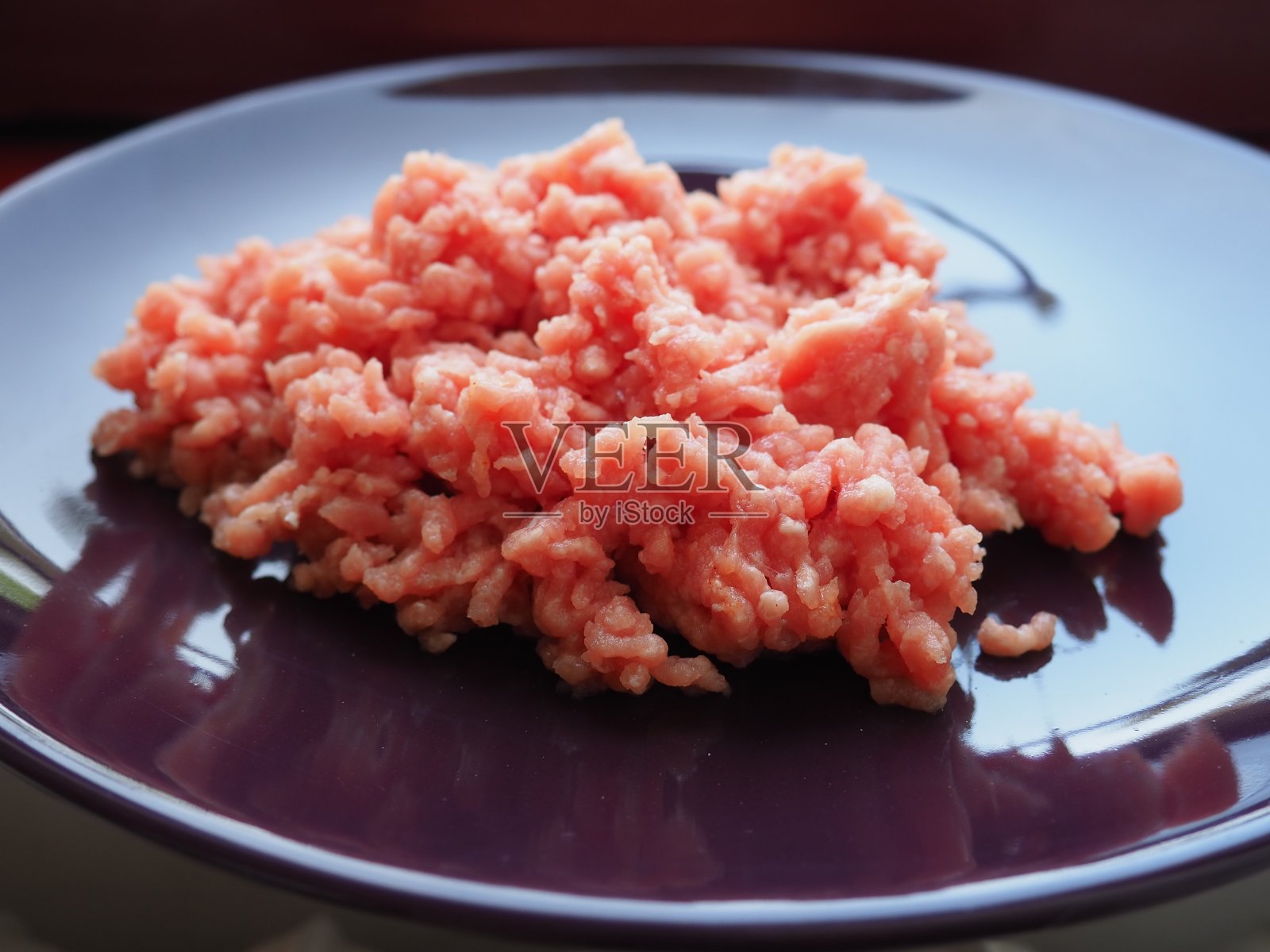 切碎的肉放在一个紫色的陶瓷大盘子里。美味的新鲜碎肉，用于制作肉排，牛排，汉堡，肉丸。猪肉半成品照片摄影图片