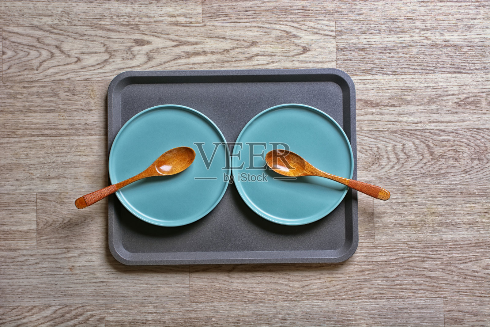 木桌上放着一个托盘，两个盘子和两个勺子——特写镜头照片摄影图片