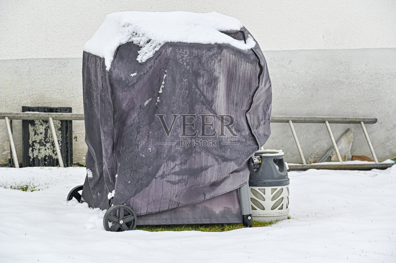 盖着煤气的烤架站在外面的雪照片摄影图片