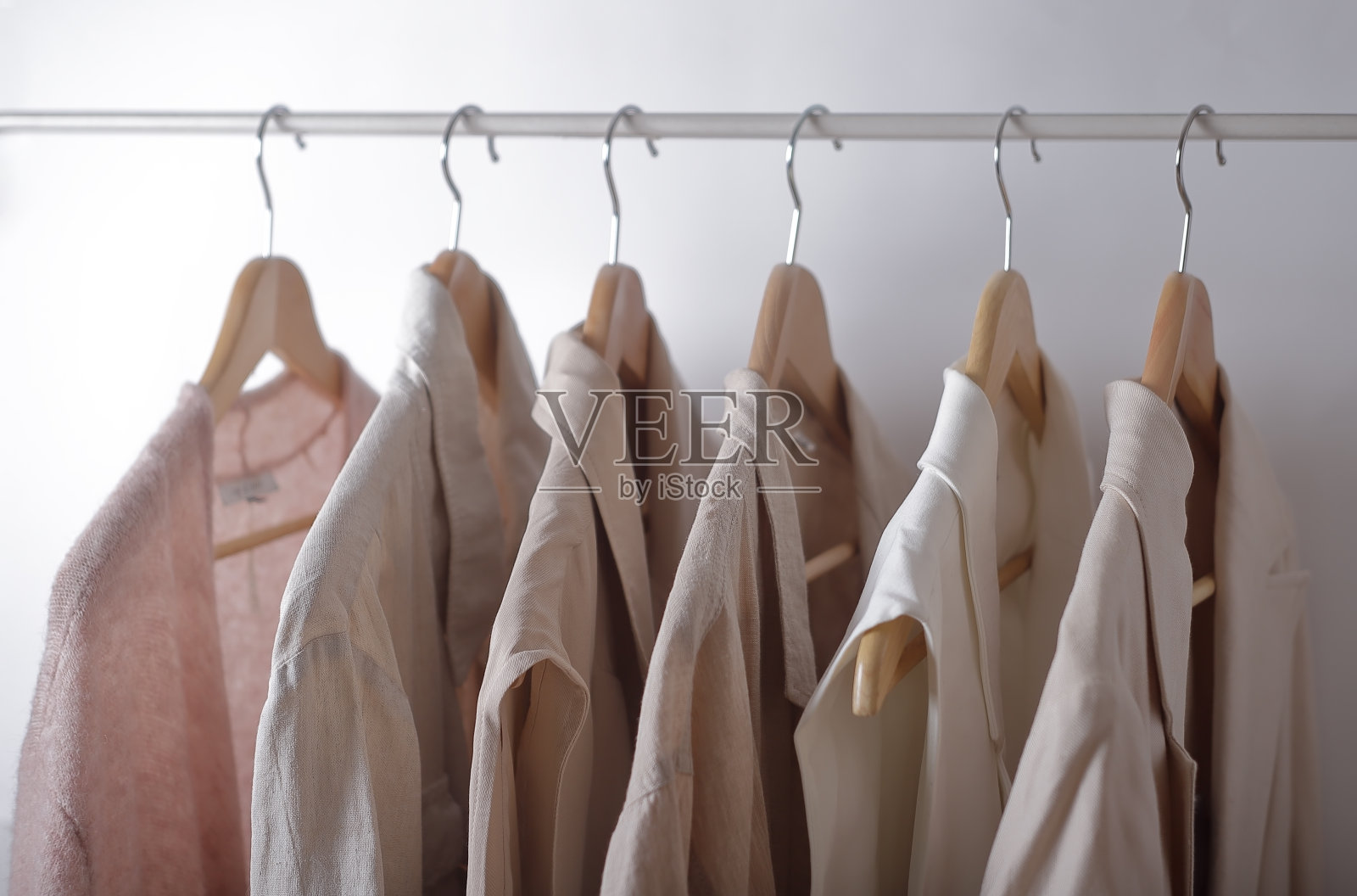 挂在衣架上的浅色衣服。照片摄影图片