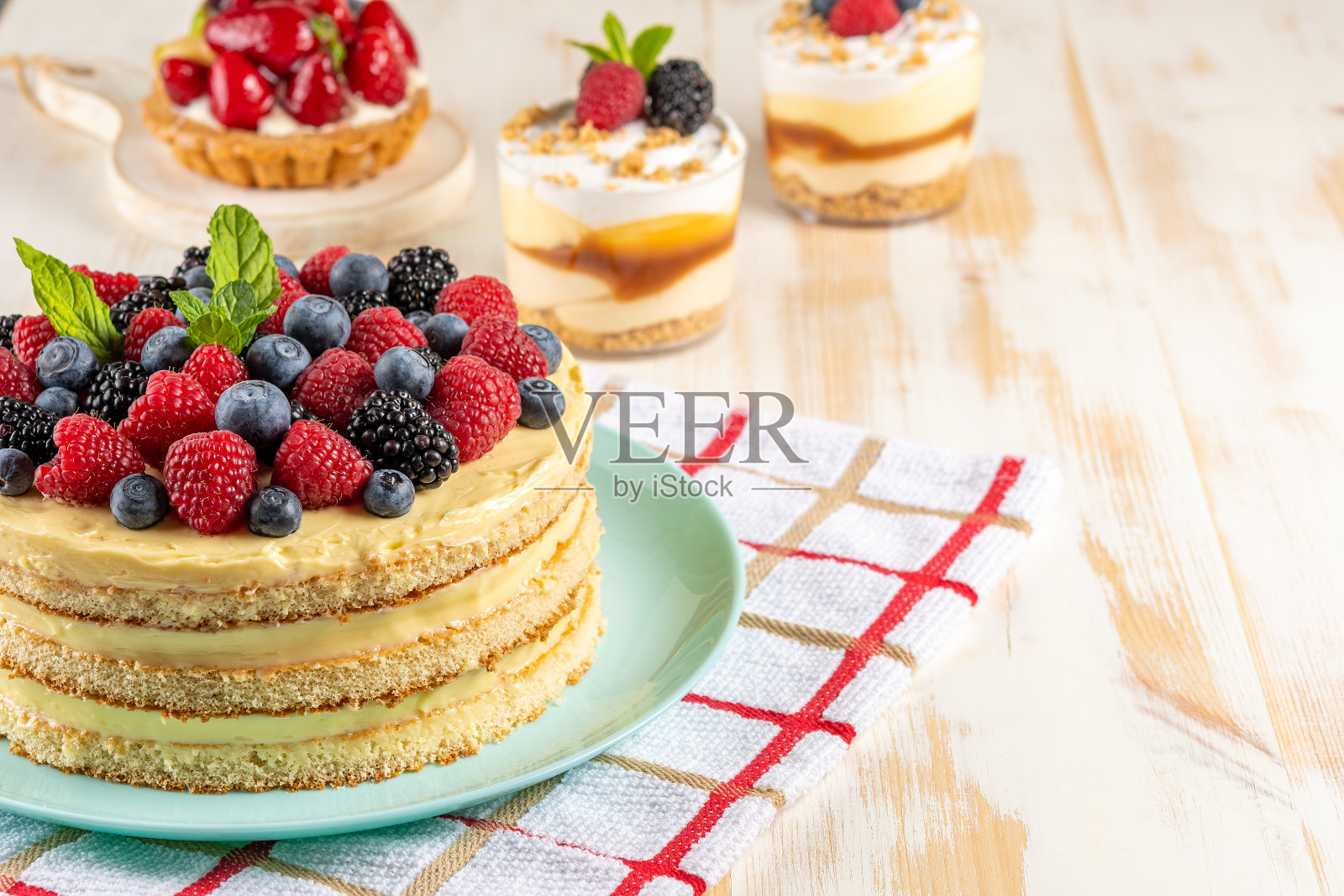 自制的蛋糕与新鲜的浆果在木制的背景。照片摄影图片