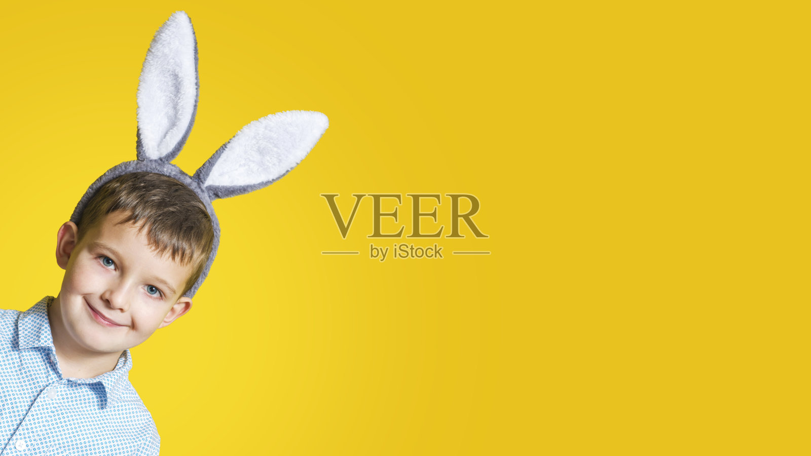 可爱的微笑男孩的肖像戴着复活节兔子耳朵在黄色的背景。副本的空间。复活节快乐。复活节销售。照片摄影图片