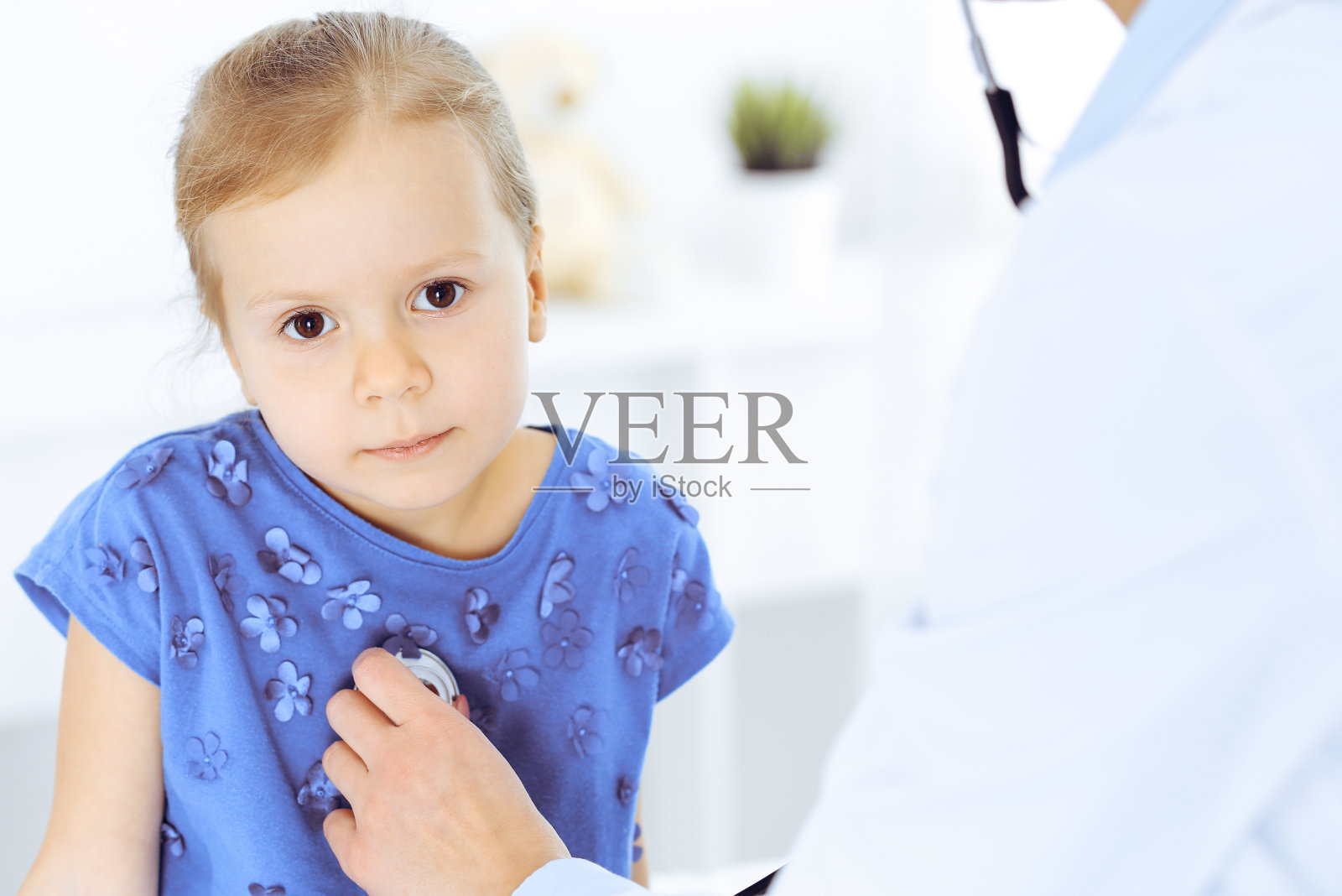 医生正在用听诊器检查一个小女孩。开心微笑的孩子病人在平时的医疗检查。医学和保健概念照片摄影图片