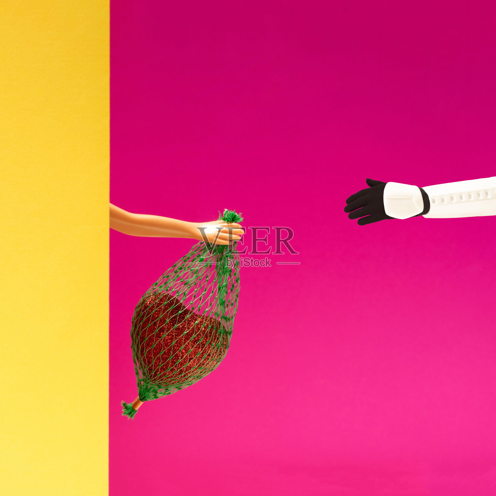 最小布置的女娃娃手拿小袋子里面有心。又有一支冲锋队在等着它。浪漫的红色和黄色背景。照片摄影图片