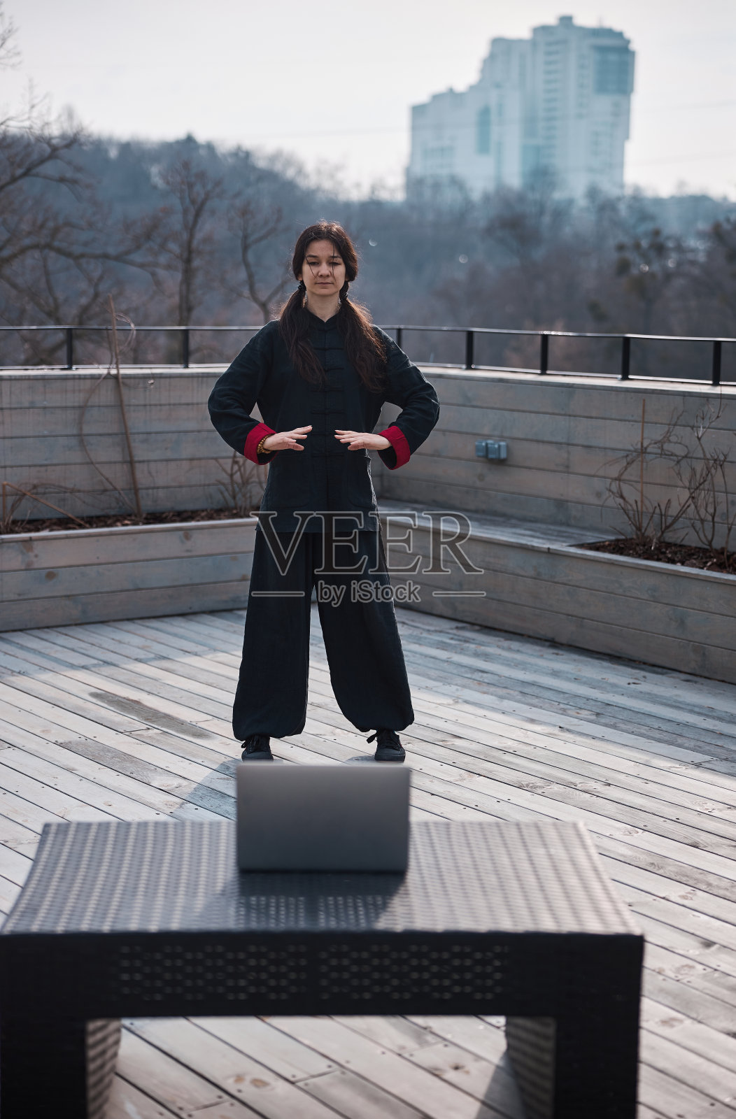 穿着武术服在笔记本电脑前打太极的女人照片摄影图片