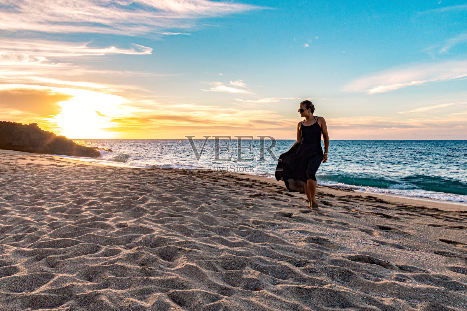 日落时分，女孩在海滩上散步照片摄影图片