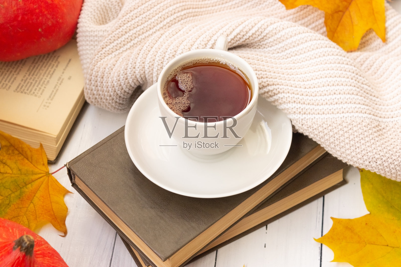 秋天的气氛。一杯茶，黄色的枫叶，一本书，还有一件编织的东西照片摄影图片