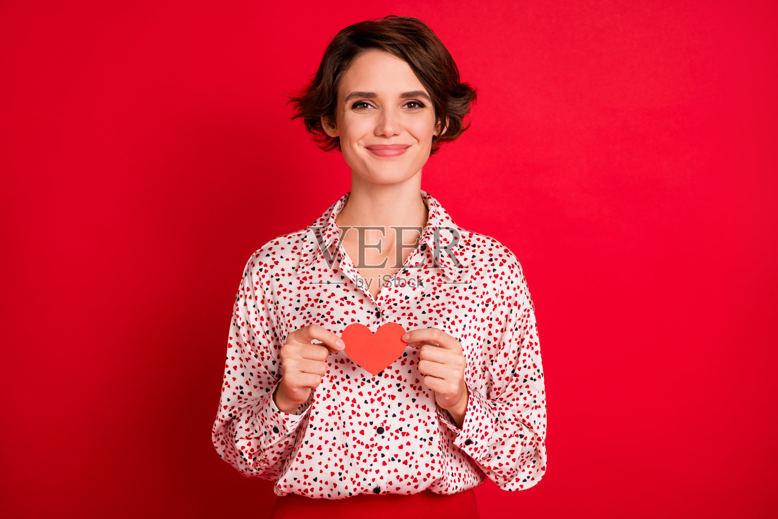 照片肖像的女人拿着小心卡在手里孤立在明亮的红色背景照片摄影图片