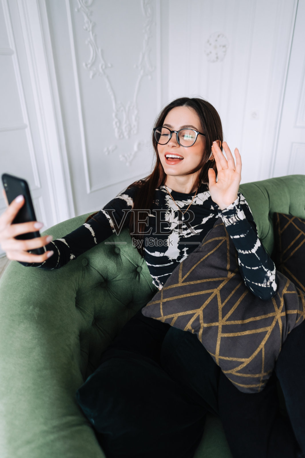 年轻的白人妇女在家里用手机视频通话，编织。与家人或朋友聊天照片摄影图片