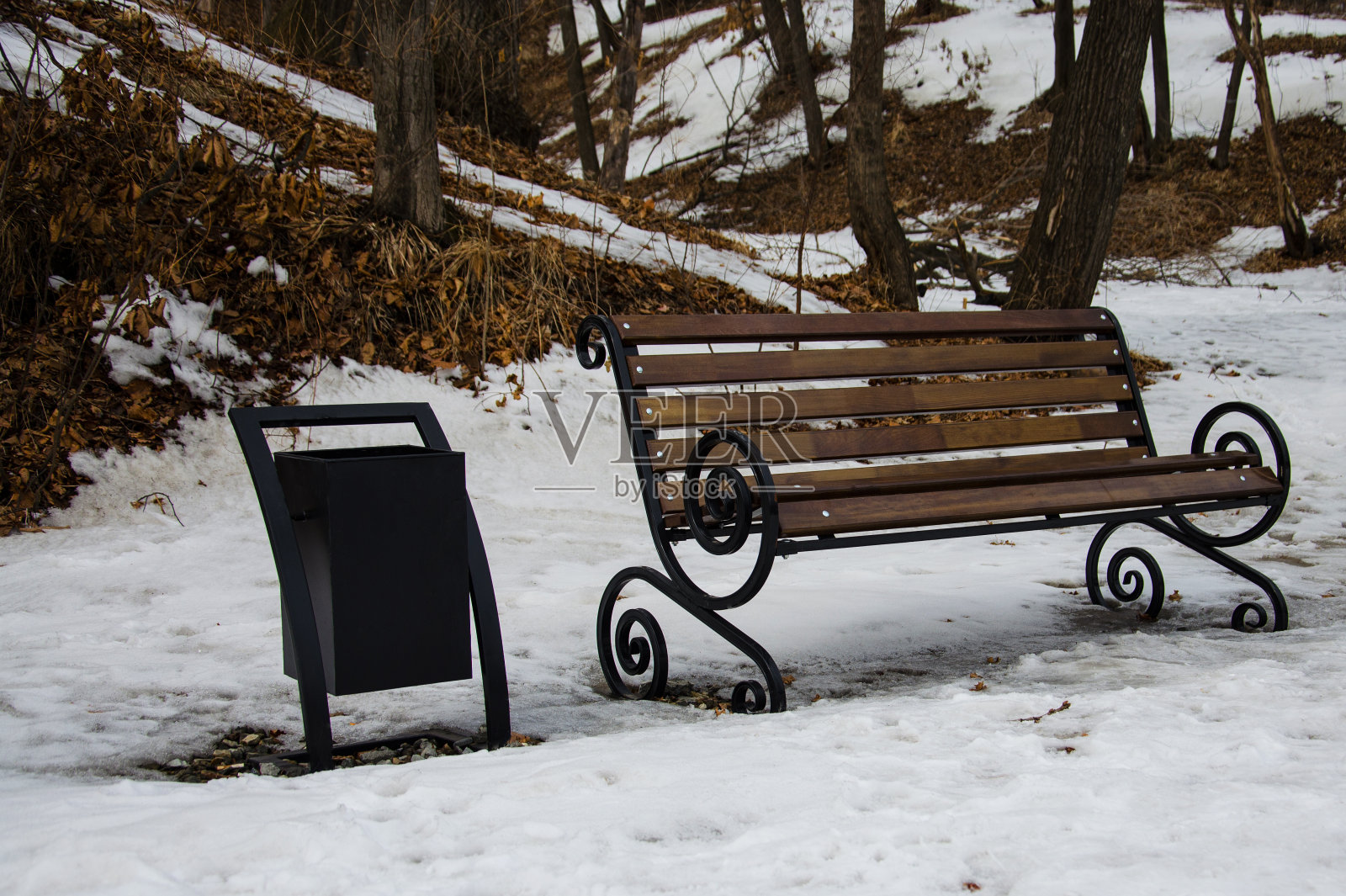 春天的公园长椅。雪泥落下的叶子选择焦点照片摄影图片