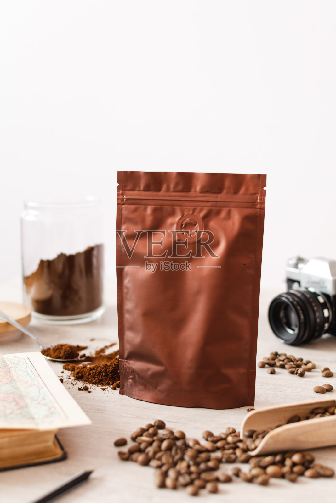 空白的咖啡包装放在木桌上，用咖啡种子，木勺放在木质背景上，咖啡包装模型用空白的空间展示您的品牌设计。照片摄影图片
