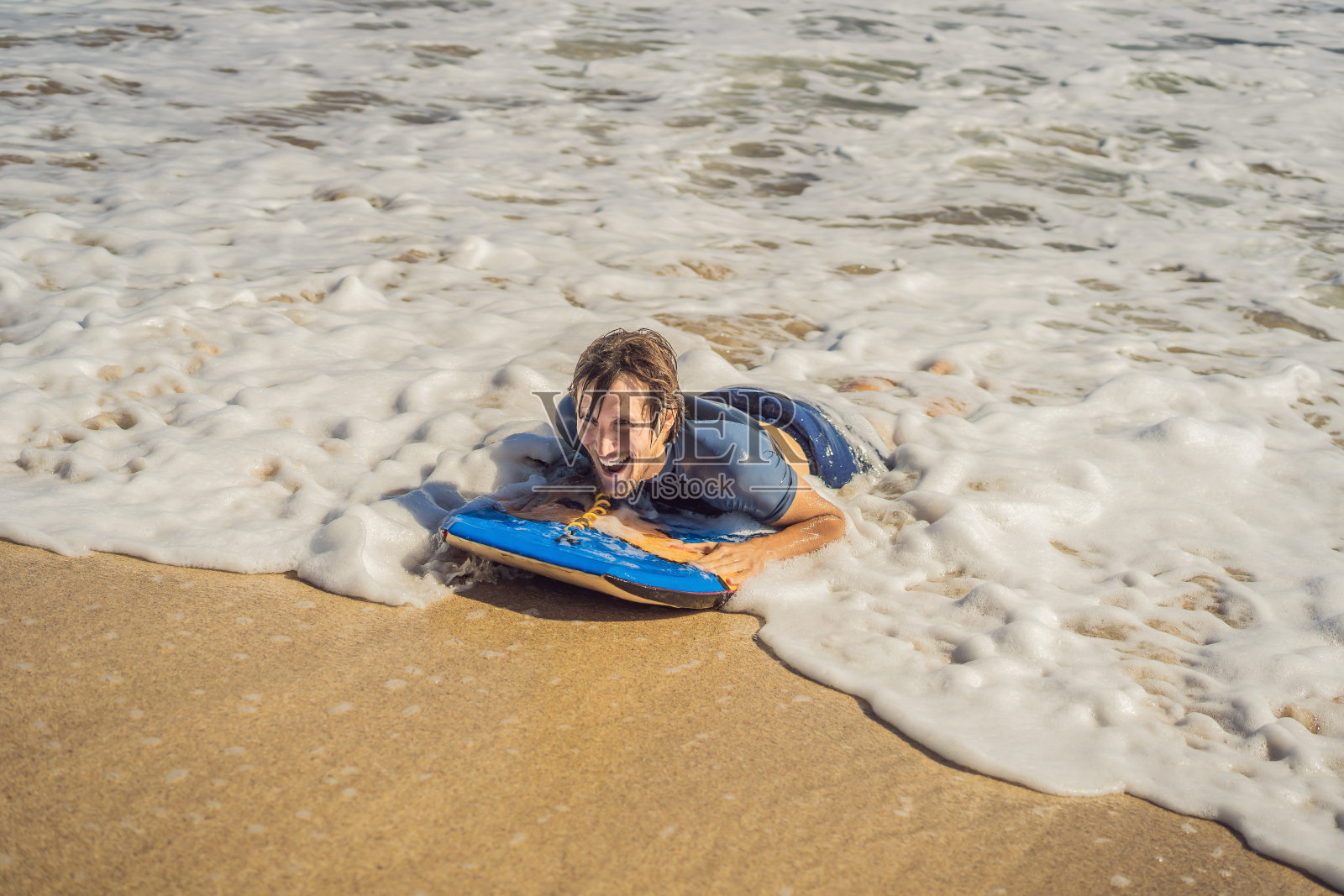 在海滩上玩冲浪板的年轻人照片摄影图片