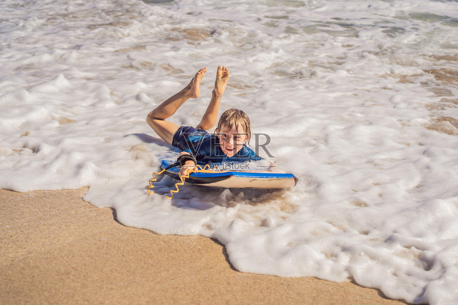 快乐的年轻男孩有乐趣在海滩度假，与布吉板照片摄影图片