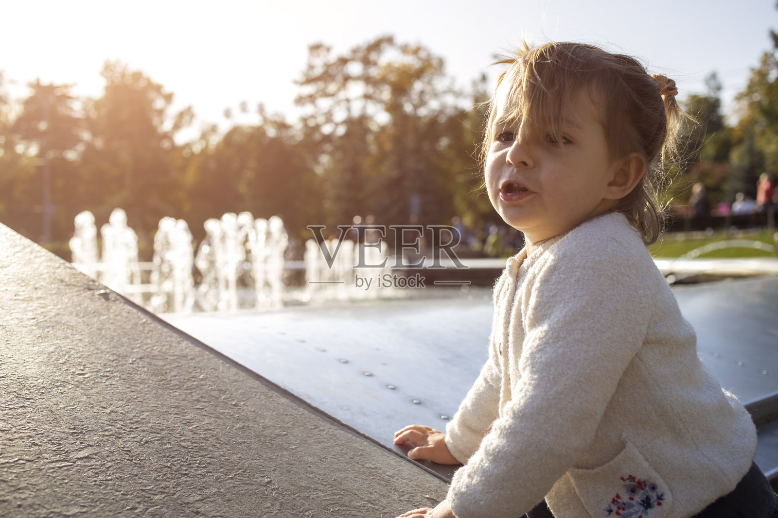 可爱的小女孩在公园的背景下做鬼脸。这孩子玩得很开心。快乐的童年照片摄影图片