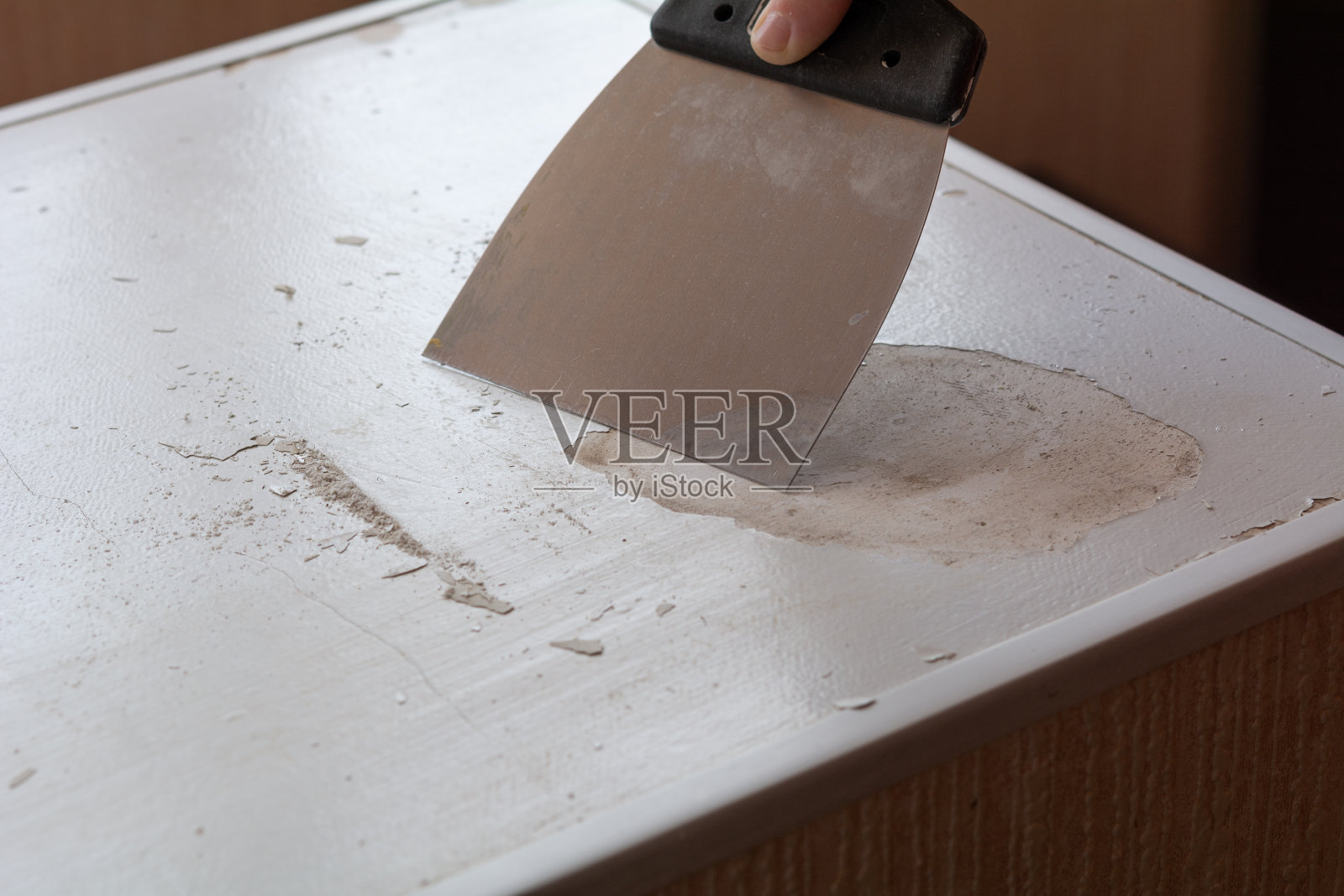 一个不知名的人用抹刀抹去一层旧漆照片摄影图片