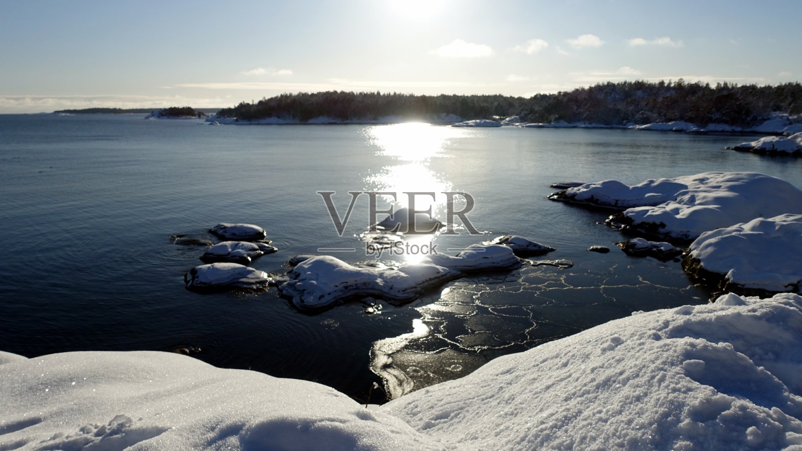 冬日早晨，阳光照耀在白雪覆盖的海湾上照片摄影图片