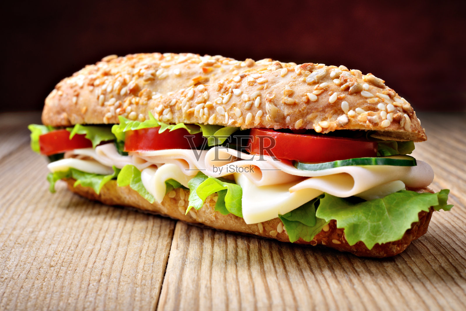 夹着火腿，奶酪，生菜，黄瓜和西红柿的三明治，特写。照片摄影图片