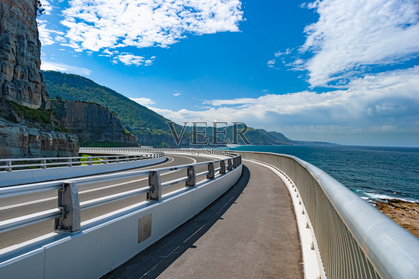 在一个阳光明媚的日子里，一座空荡荡的海洋公路桥弯弯曲曲地伸向远方照片摄影图片