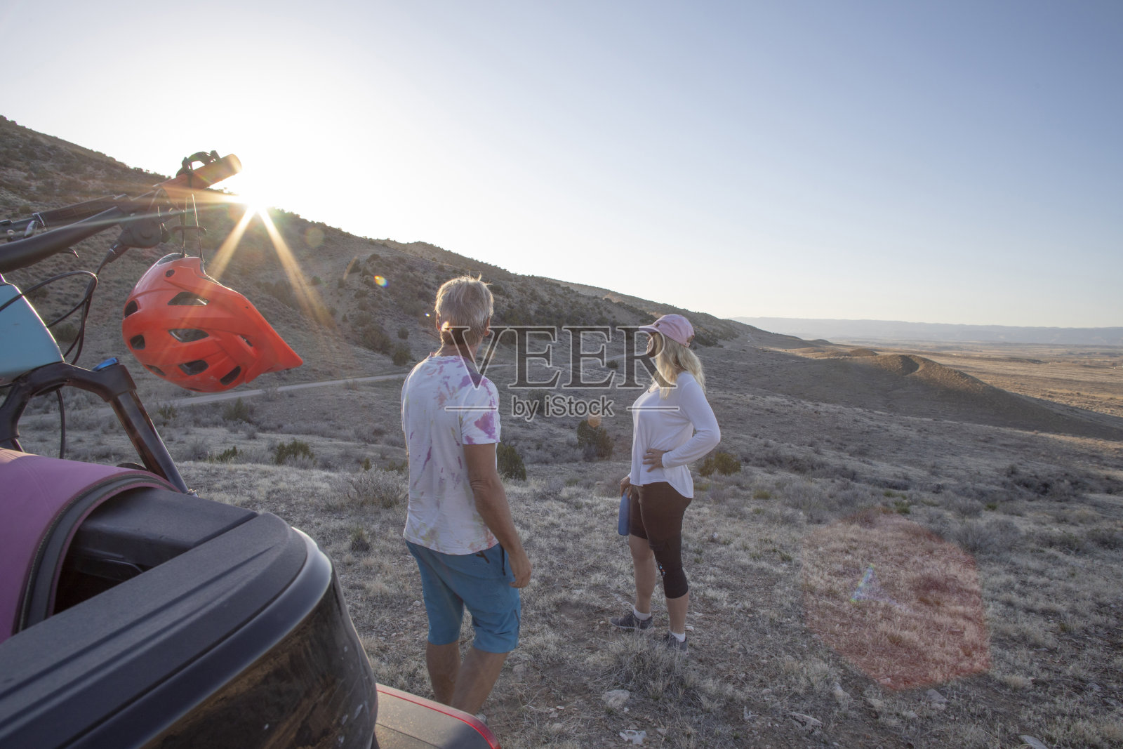 日出时分，一对成熟的夫妇在山路附近的卡车上放松照片摄影图片