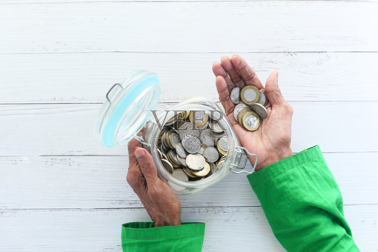 年长的妇女把手放在一个罐子里，自上而下照片摄影图片