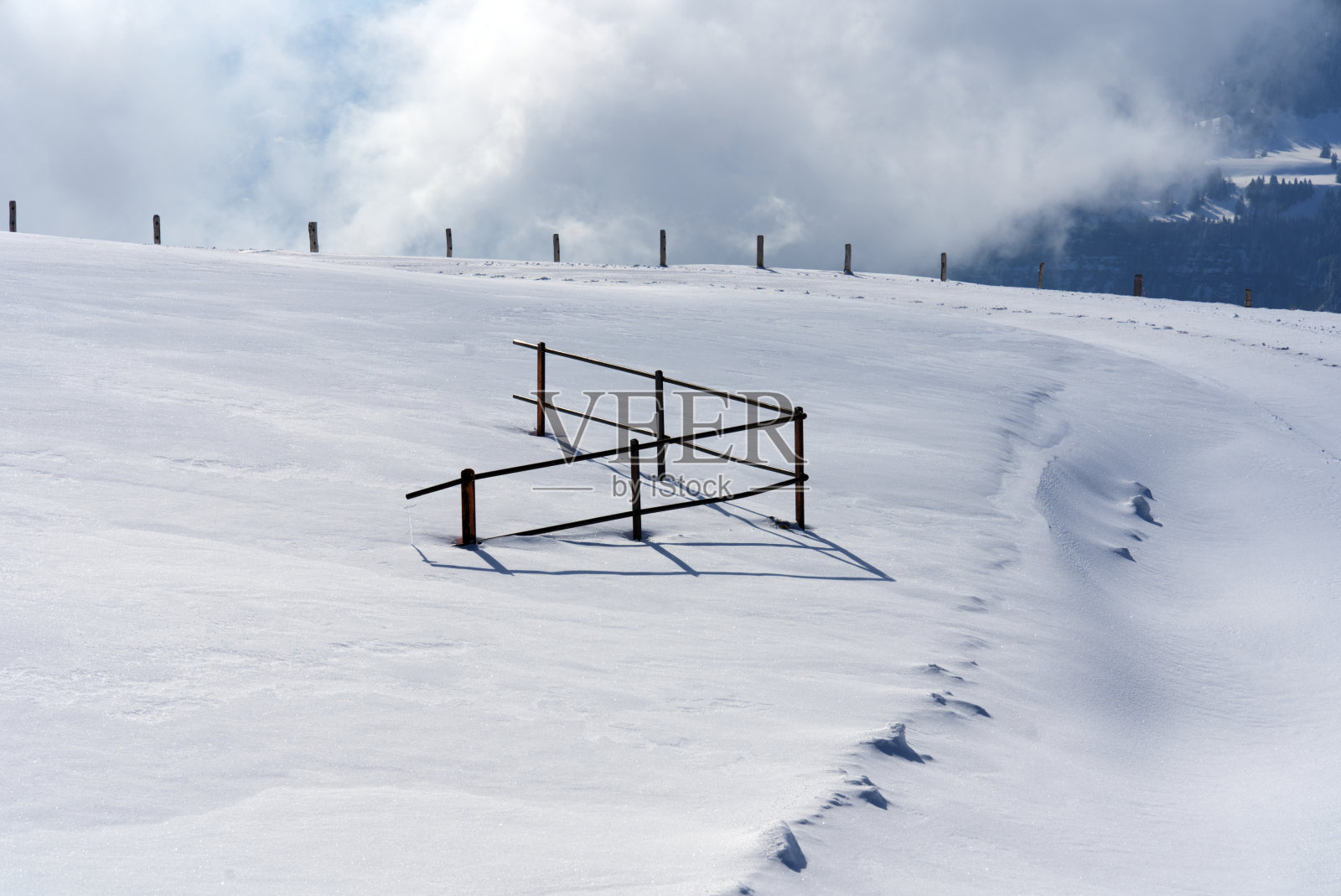 雪地里的铁栅栏有背光。照片摄影图片