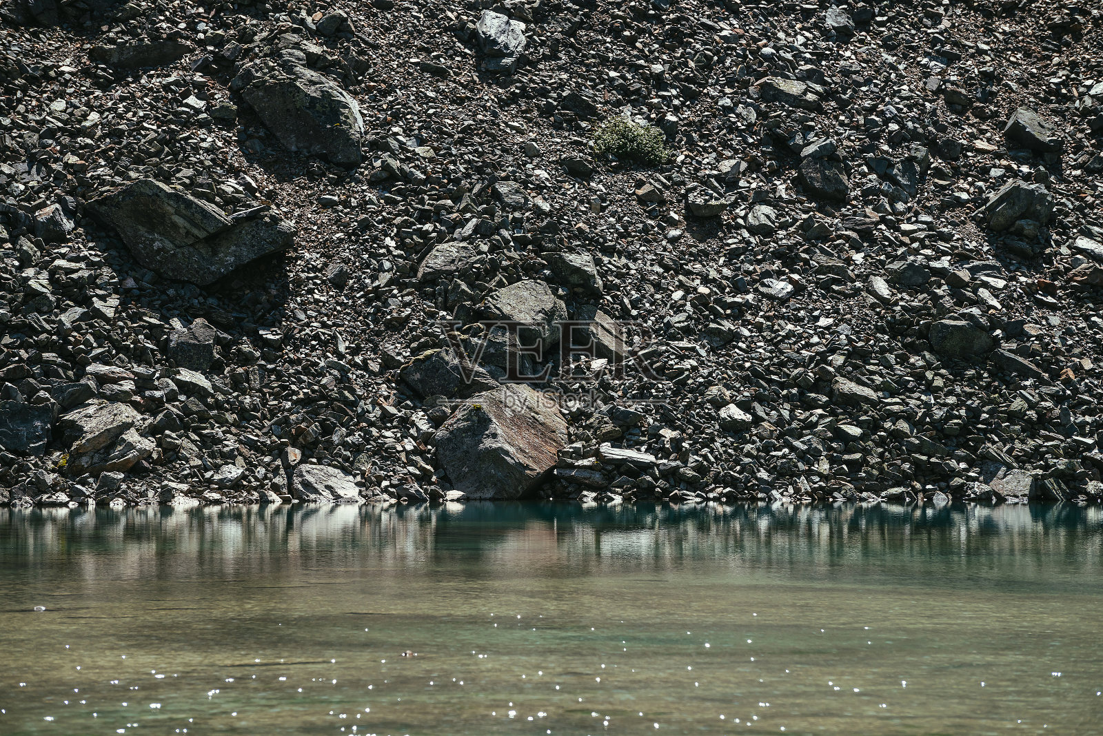 美丽的风景与阳光闪烁在绿松石水面。阳光下蔚蓝色的冰湖。冰川湖上的反射光。丰富多彩的自然风光，有山湖和石山。照片摄影图片