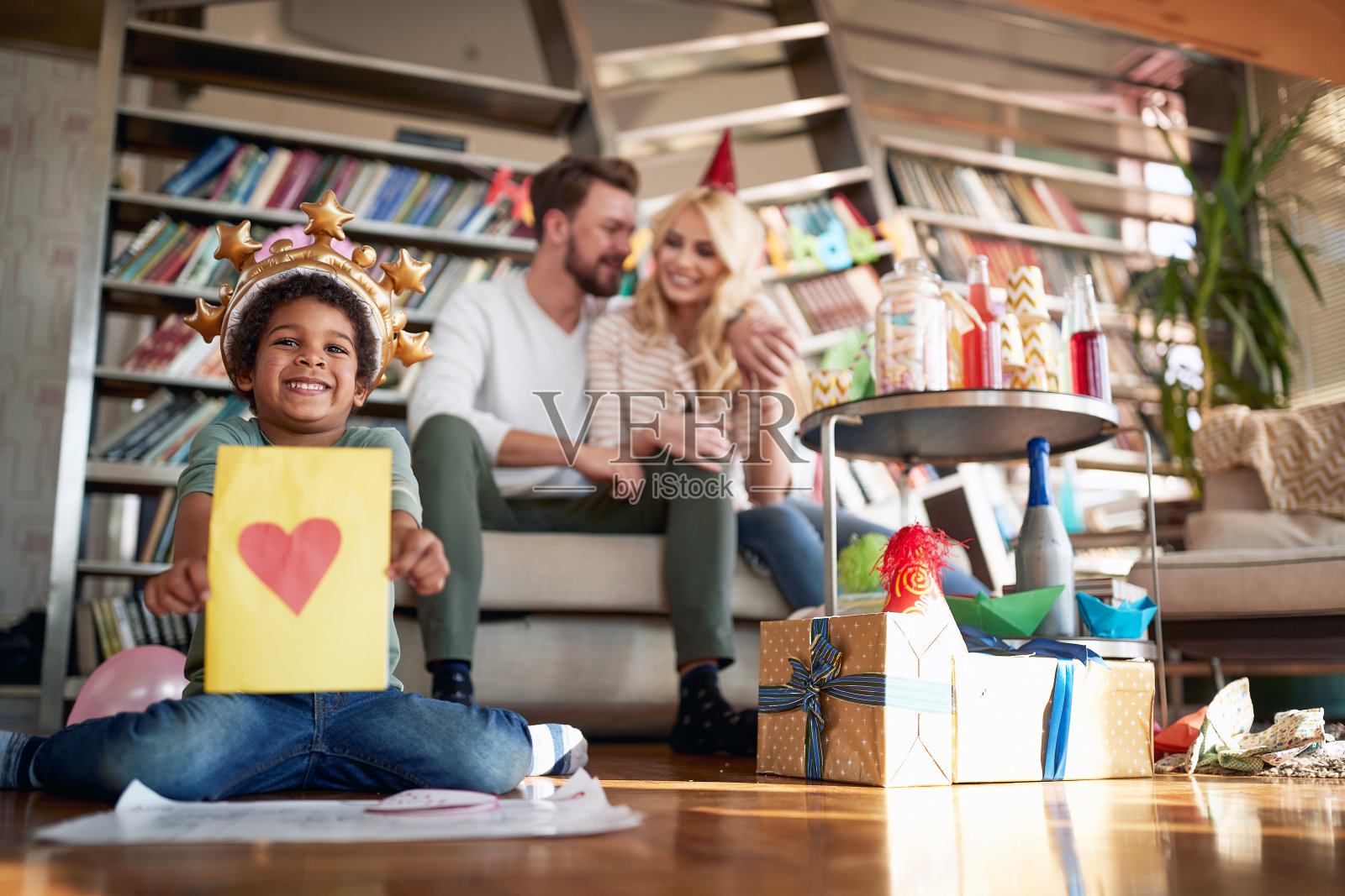 一个被收养的小男孩和他的家人在一个孩子的生日聚会上摆姿势并展示他的画。家庭,一起庆祝,照片摄影图片