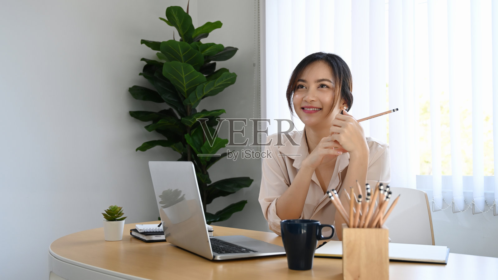 快乐的女商人坐在她的工作场所，梦想着美好的未来。照片摄影图片