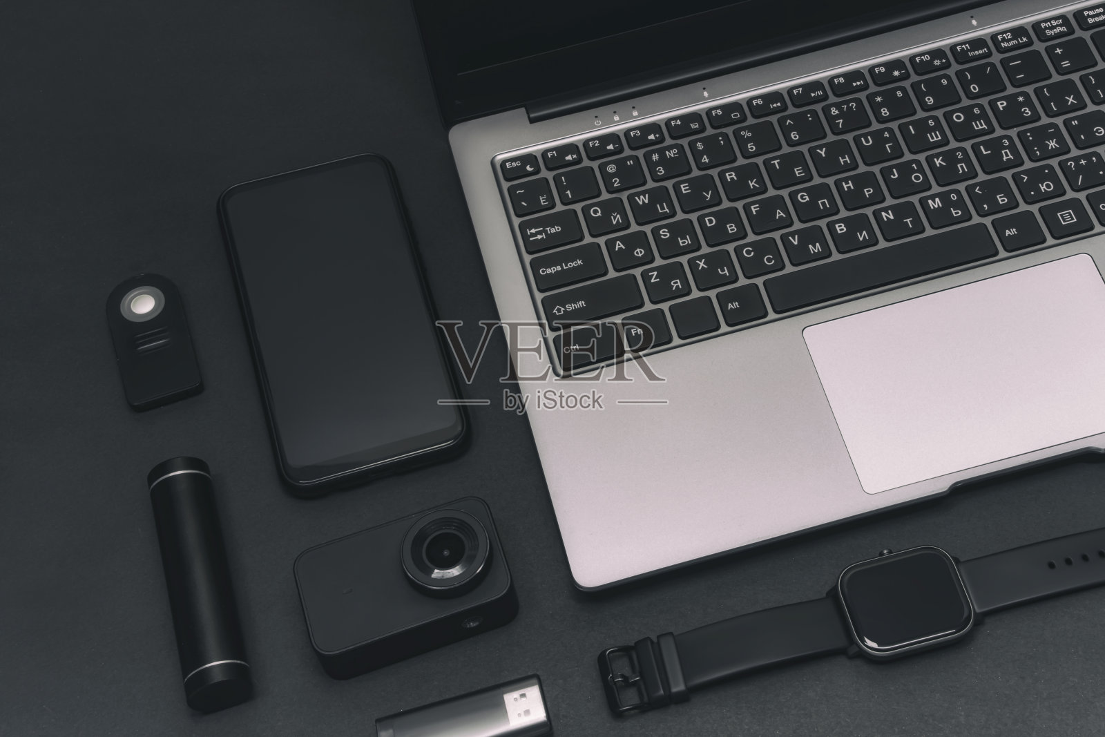 一套多媒体设备。一台带摄像头的笔记本电脑，一部智能手机，一块智能手表，还有一个黑色背景的USB移动电源。照片摄影图片