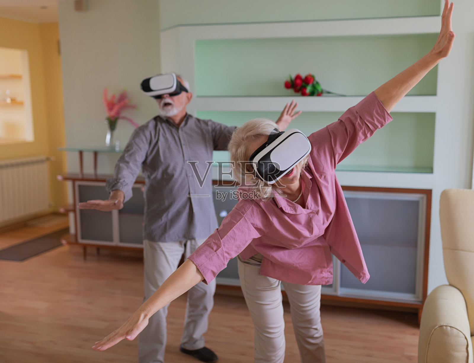 一对老年夫妇在家里一起坐在沙发上使用虚拟现实头盔照片摄影图片