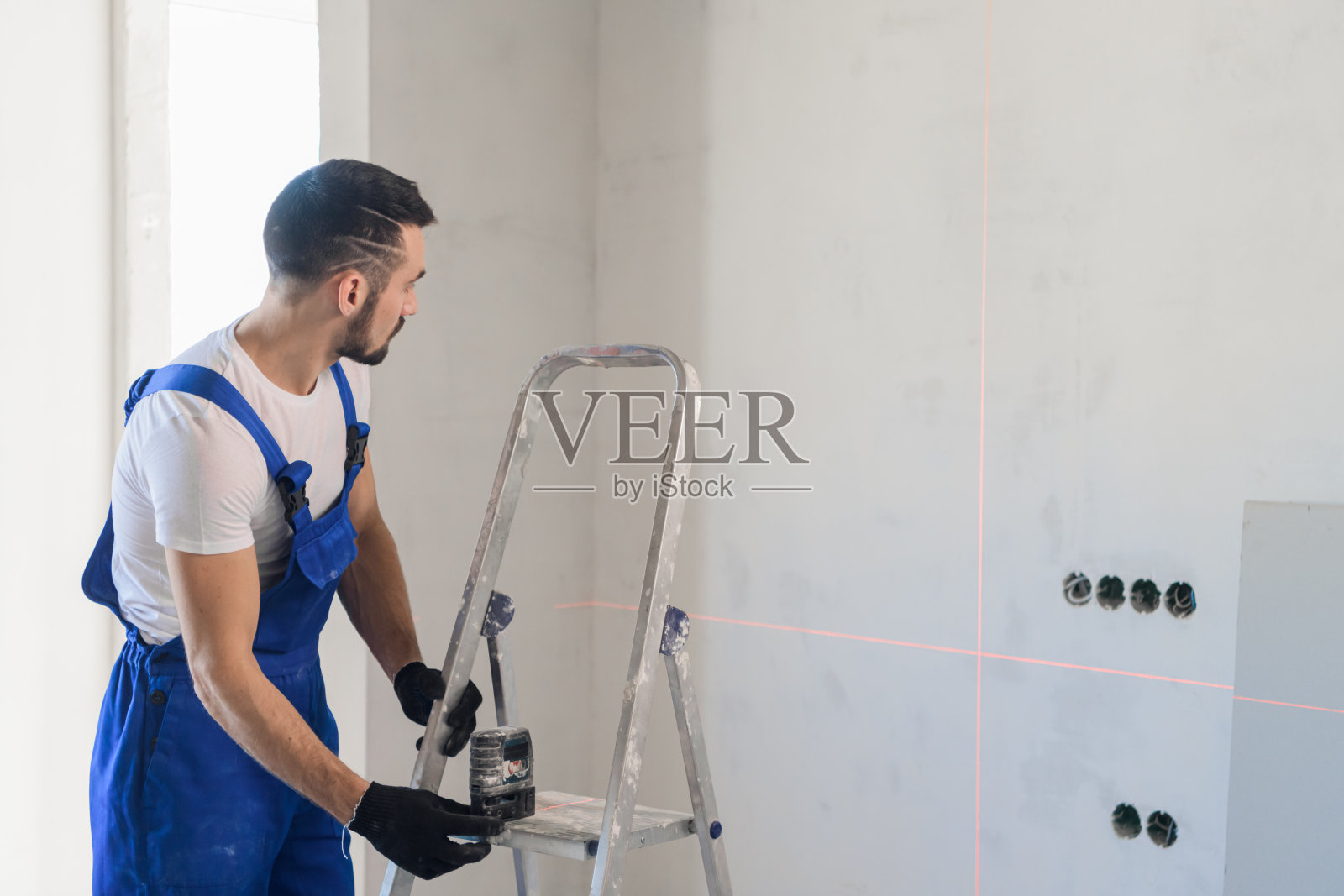 勤杂工用激光标尺在墙上做了标记照片摄影图片